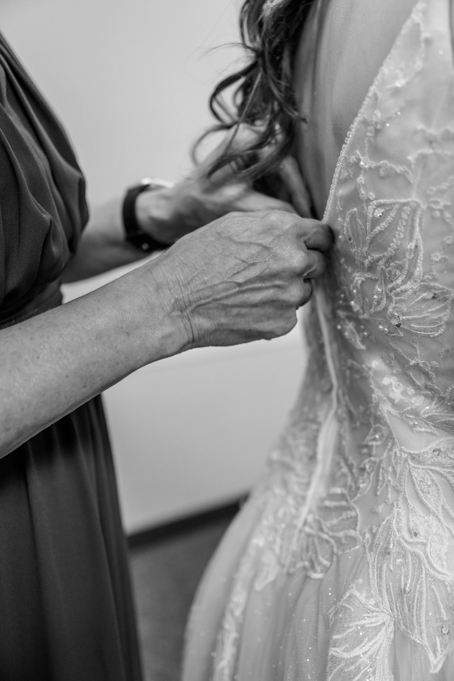 Close-up shots showing hands adjusting delicate lace details and beading on a white wedding dress.