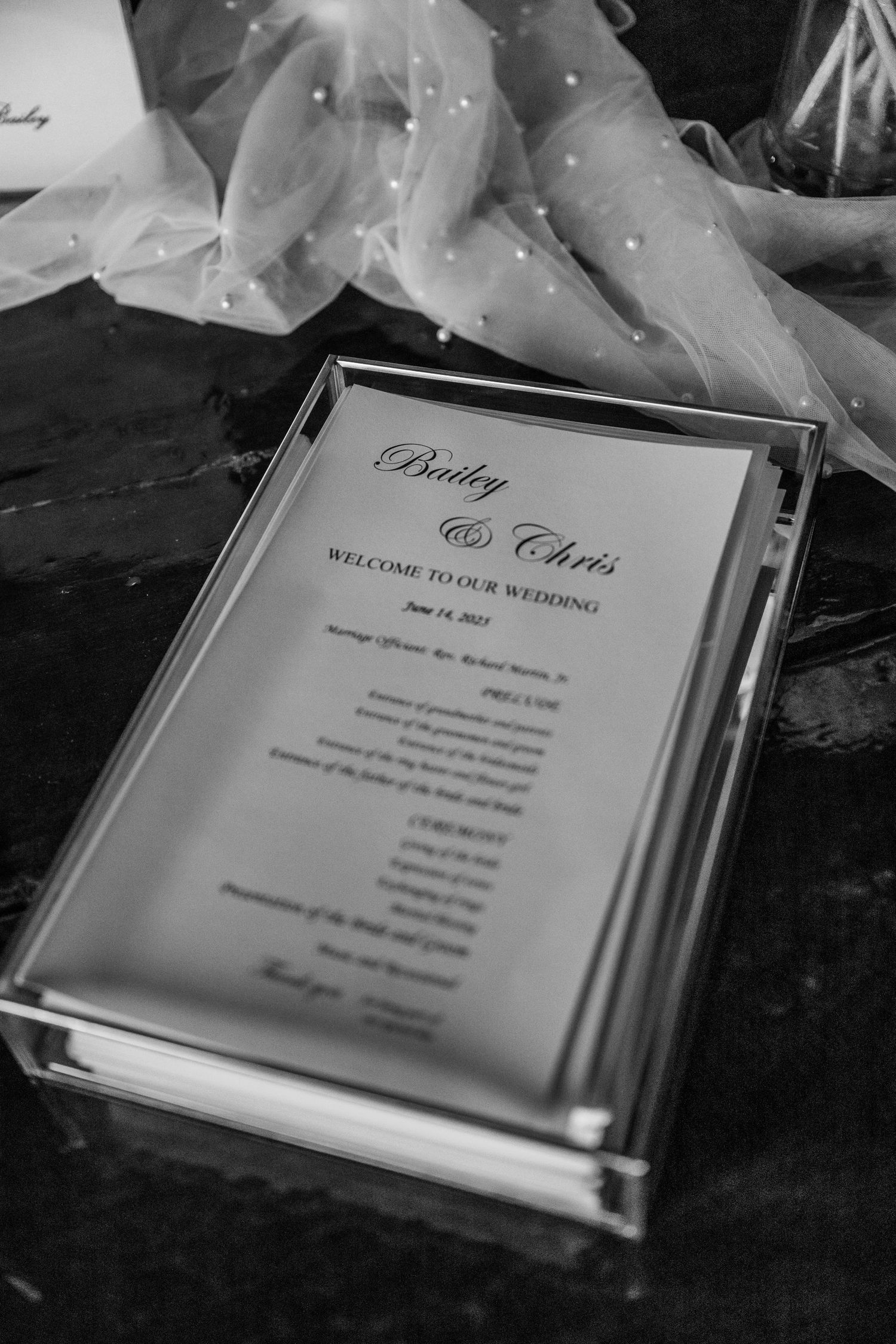 Black and white wedding invitation details with elegant typography and menu cards displayed on a dark surface.