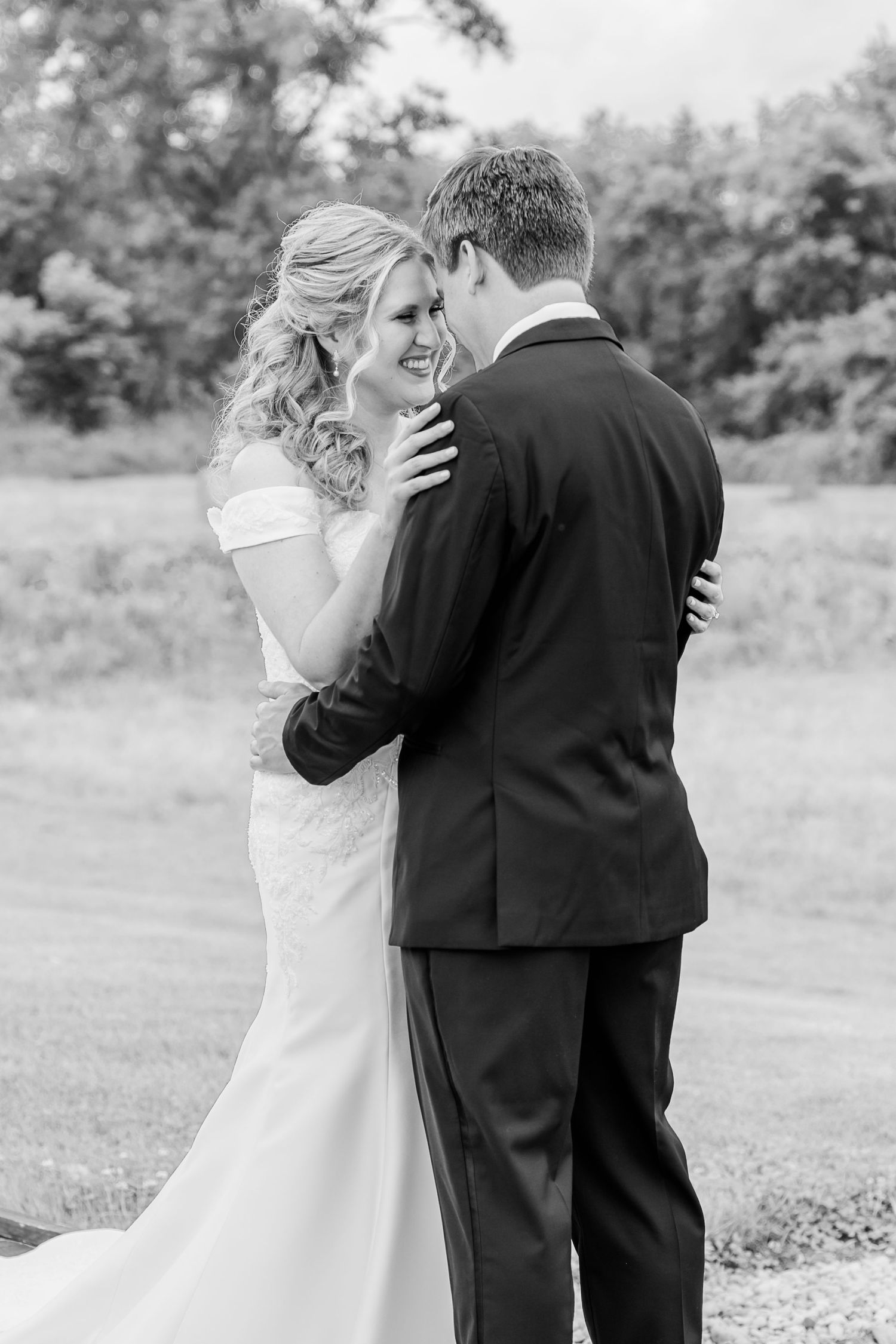 Black and white photo showing a romantic first look moment between newlyweds in an outdoor garden setting.The Old Barns at Dry Run Farms