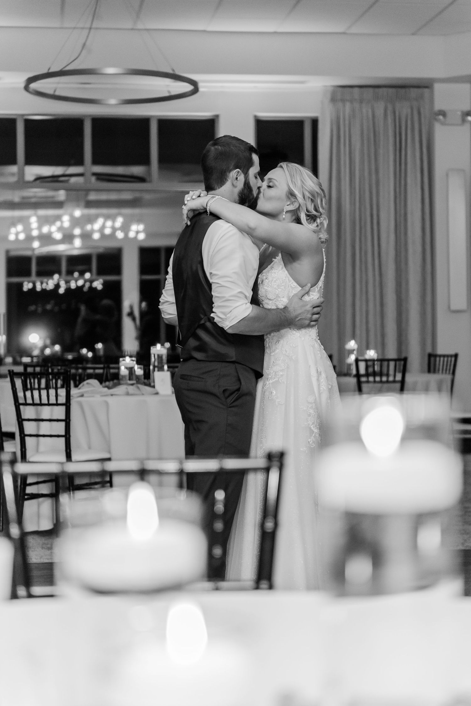 A romantic first dance moment at a wedding reception with candlelit tables in the foreground.