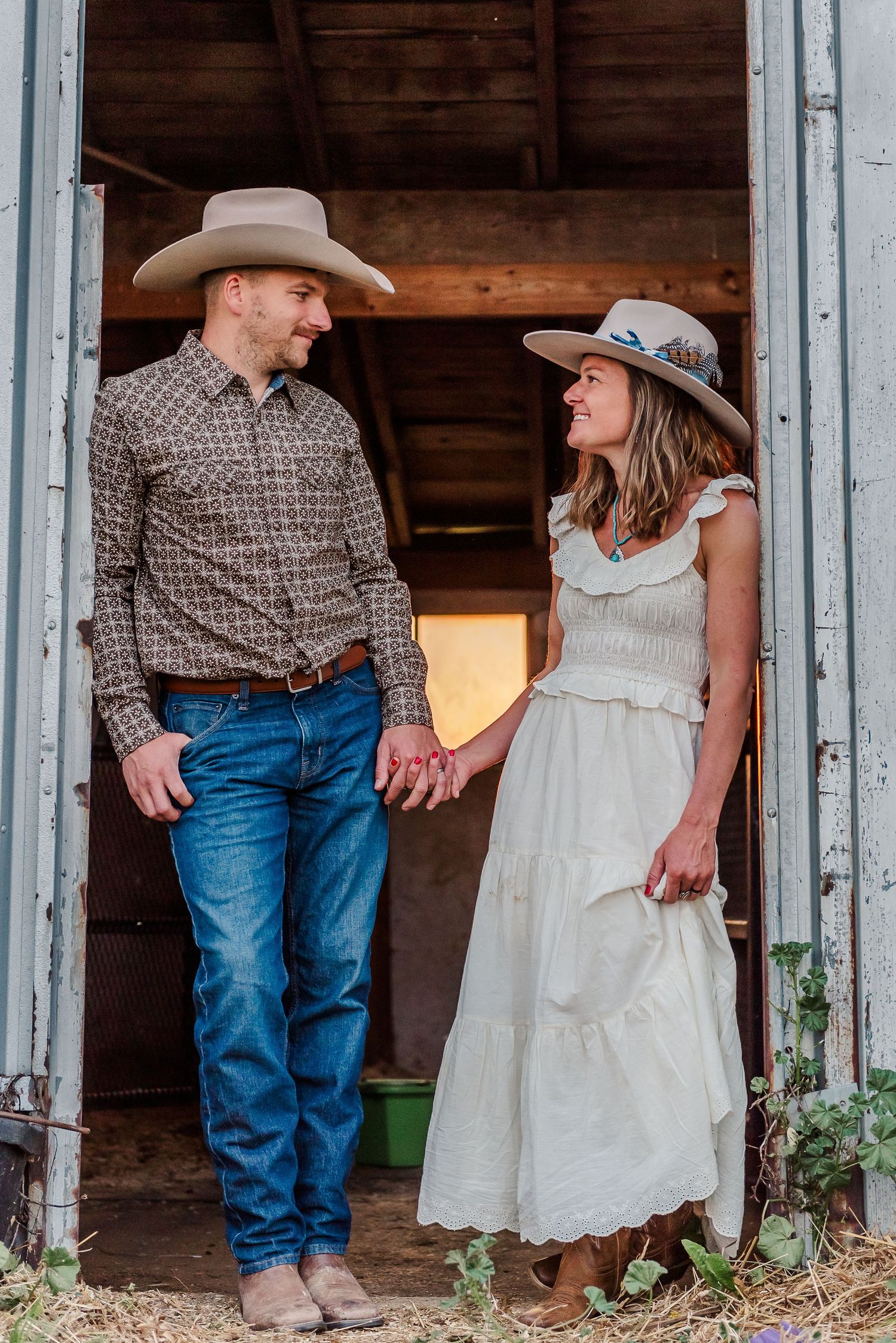 Rustic barn scene with couples in cowboy boots and western attire standing in a weathered doorway.
