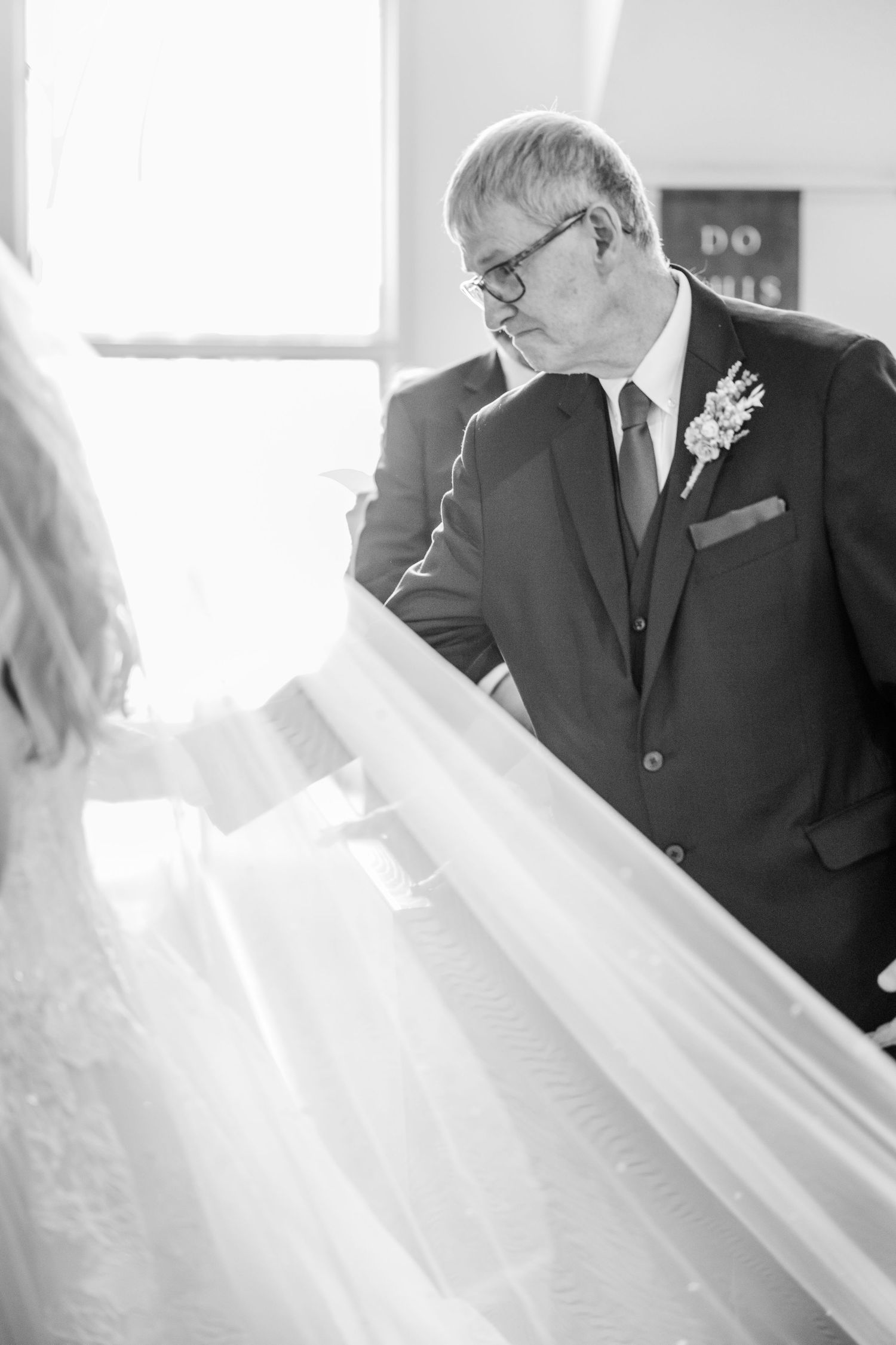Emotional black and white wedding moment as father looks at bride in her wedding dress.