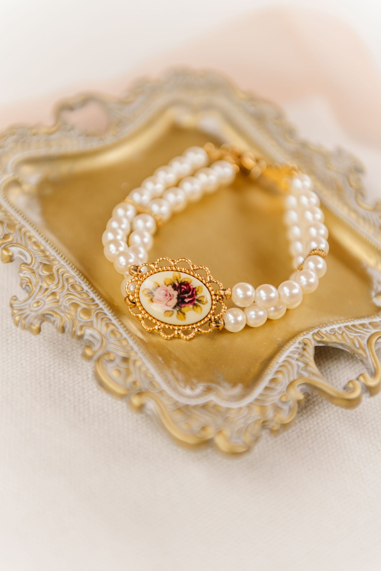 Elegant pearl bracelet with vintage gold clasp displayed on cream-colored lace background in multiple angles.