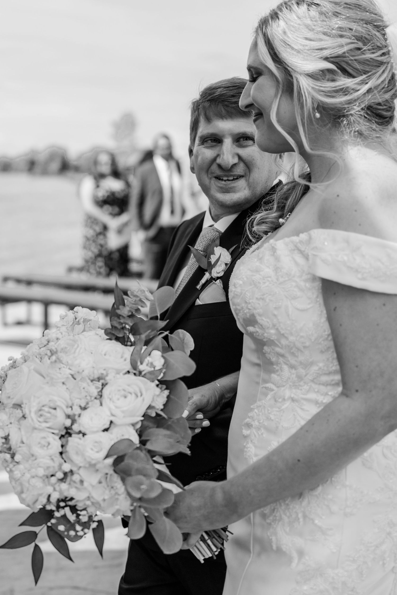 A wedding couple shares intimate moments while holding elegant white bouquets in a series of black and white photos.