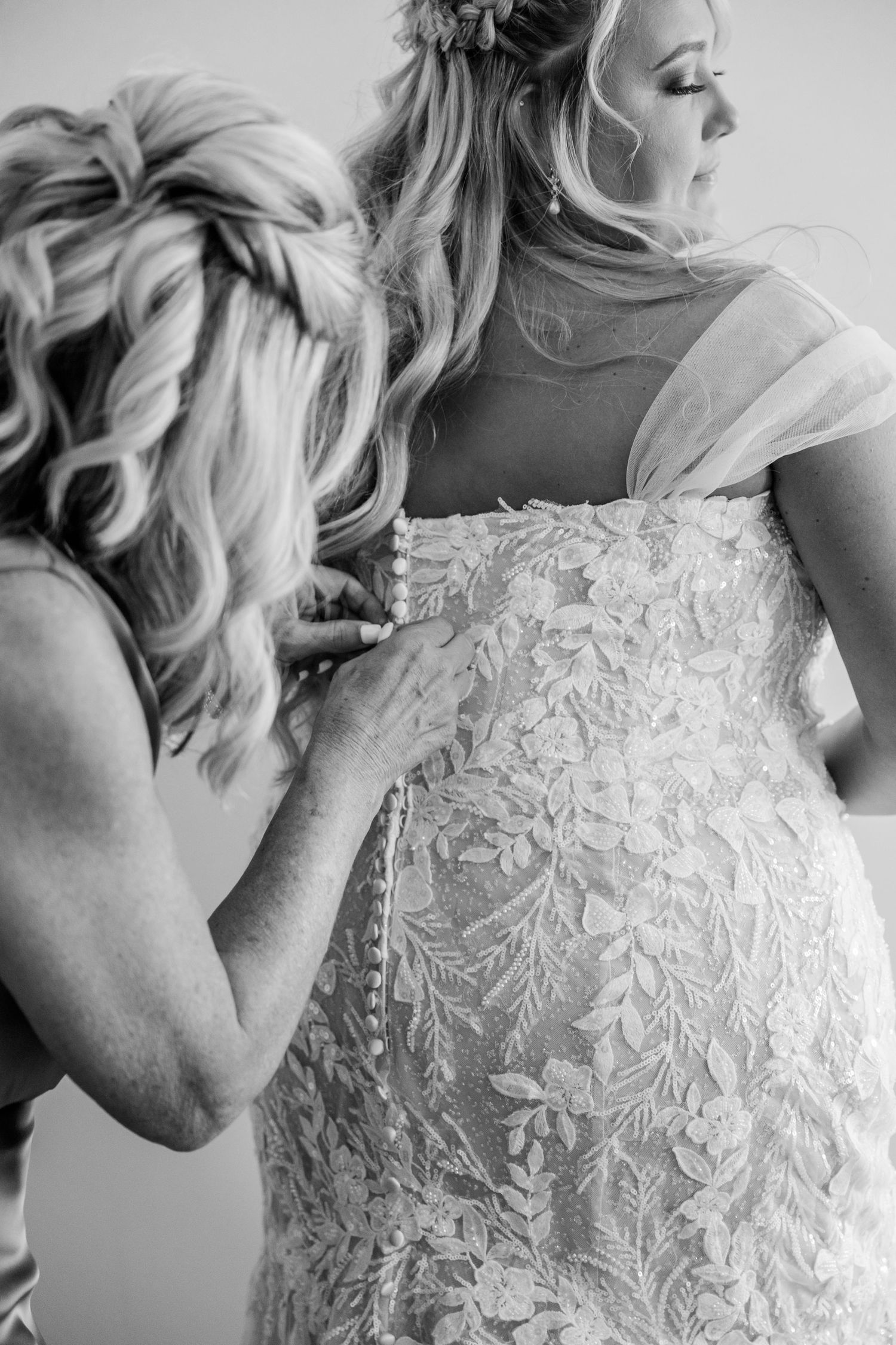 A black and white photo series showing intricate details of a lace wedding dress with delicate embroidered patterns.