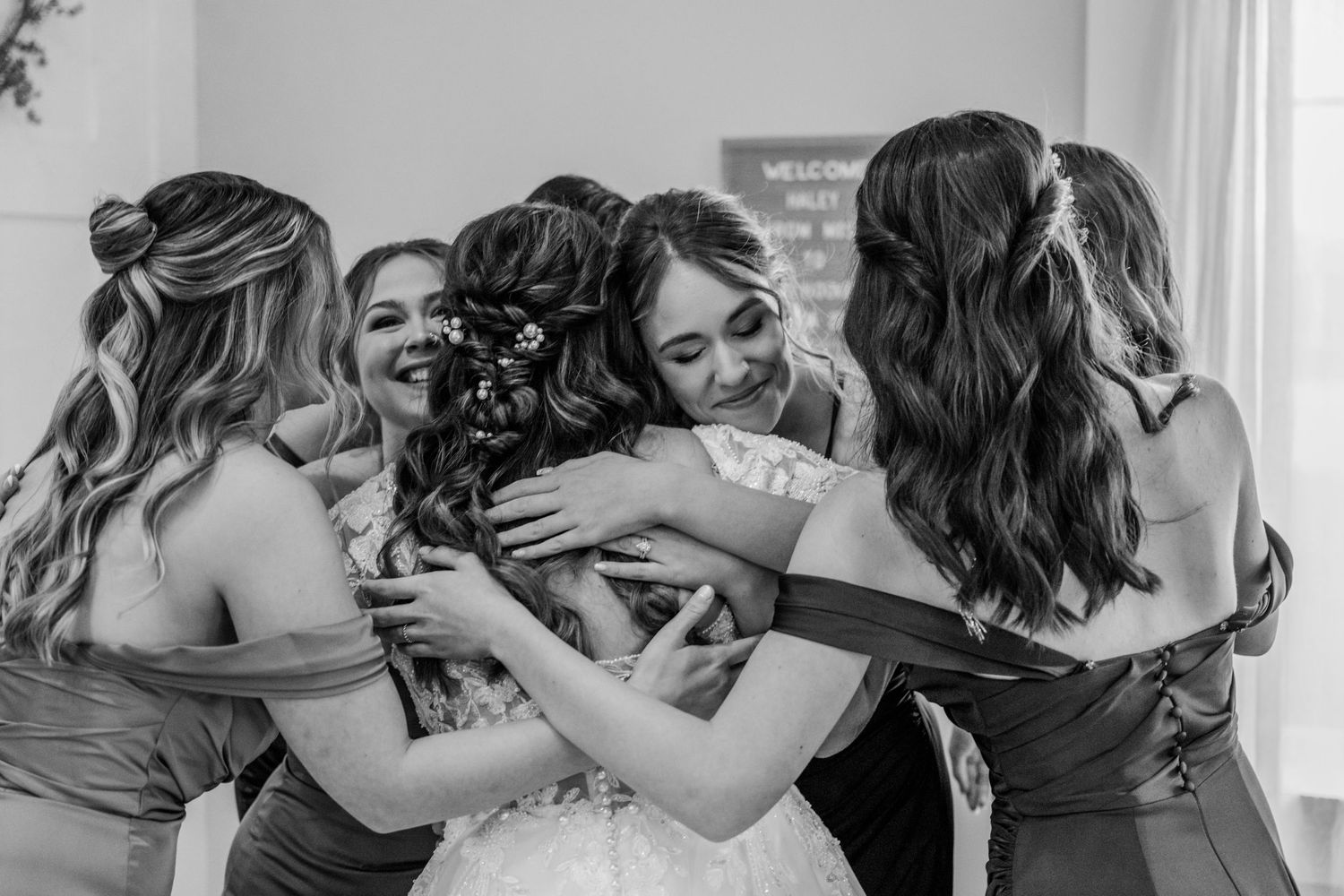 Bridesmaids in matching dresses share emotional moments while getting ready for wedding. Four Seasons Barn Wedding & Event Venue