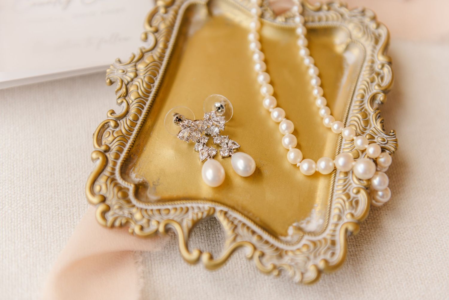 Delicate pearl and crystal bridal hair accessories displayed on elegant gold decorative frames against a soft beige background.