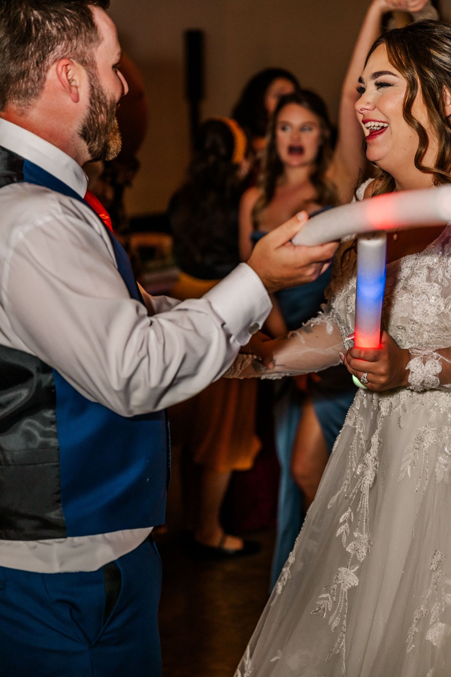 A couple shares a playful moment during their wedding dance as the groom feeds his bride a glowing light stick.Four Seasons Barn Wedding.