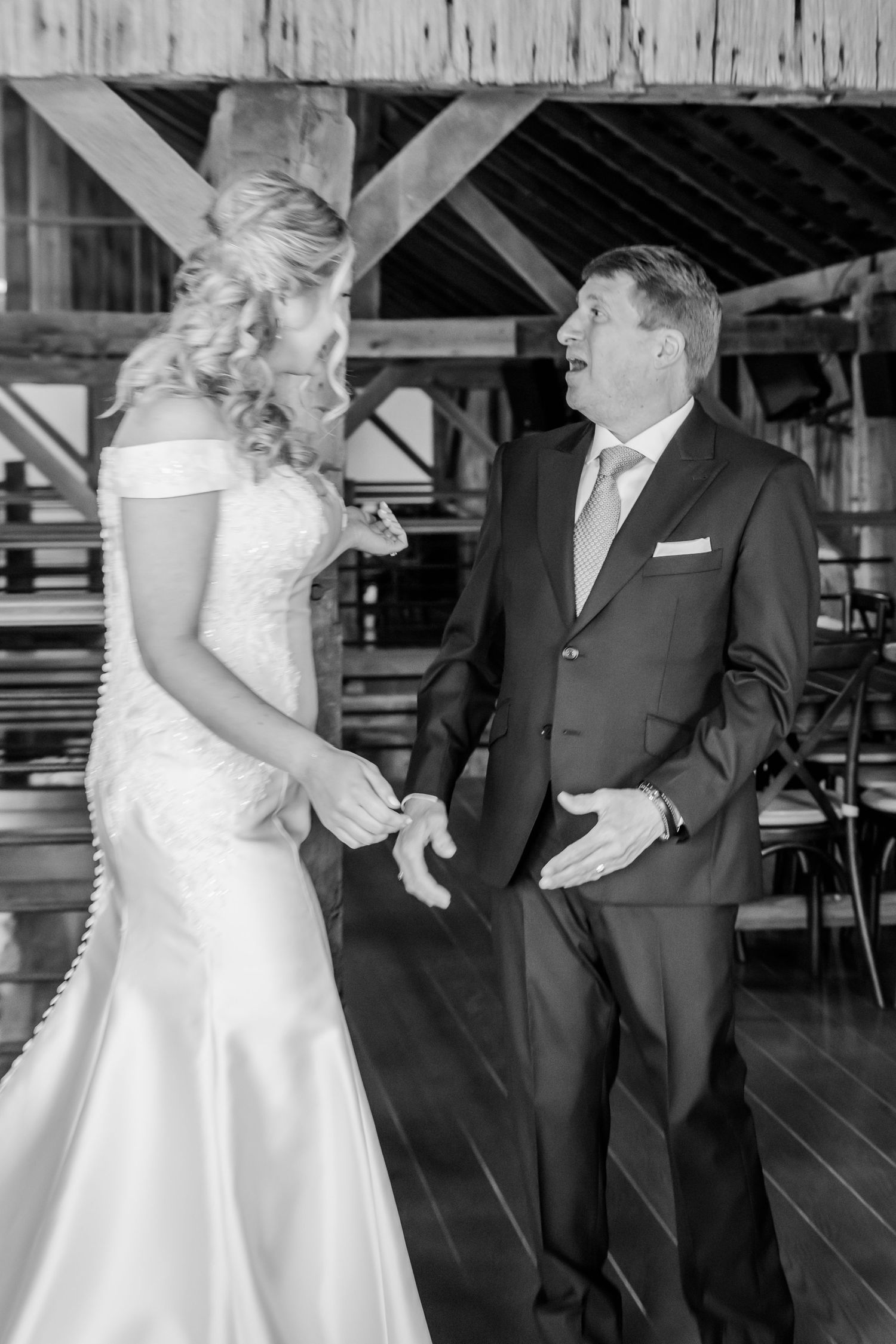 Black and white photo sequence showing an emotional first look between a bride in white dress and suited figure at a rustic venue.