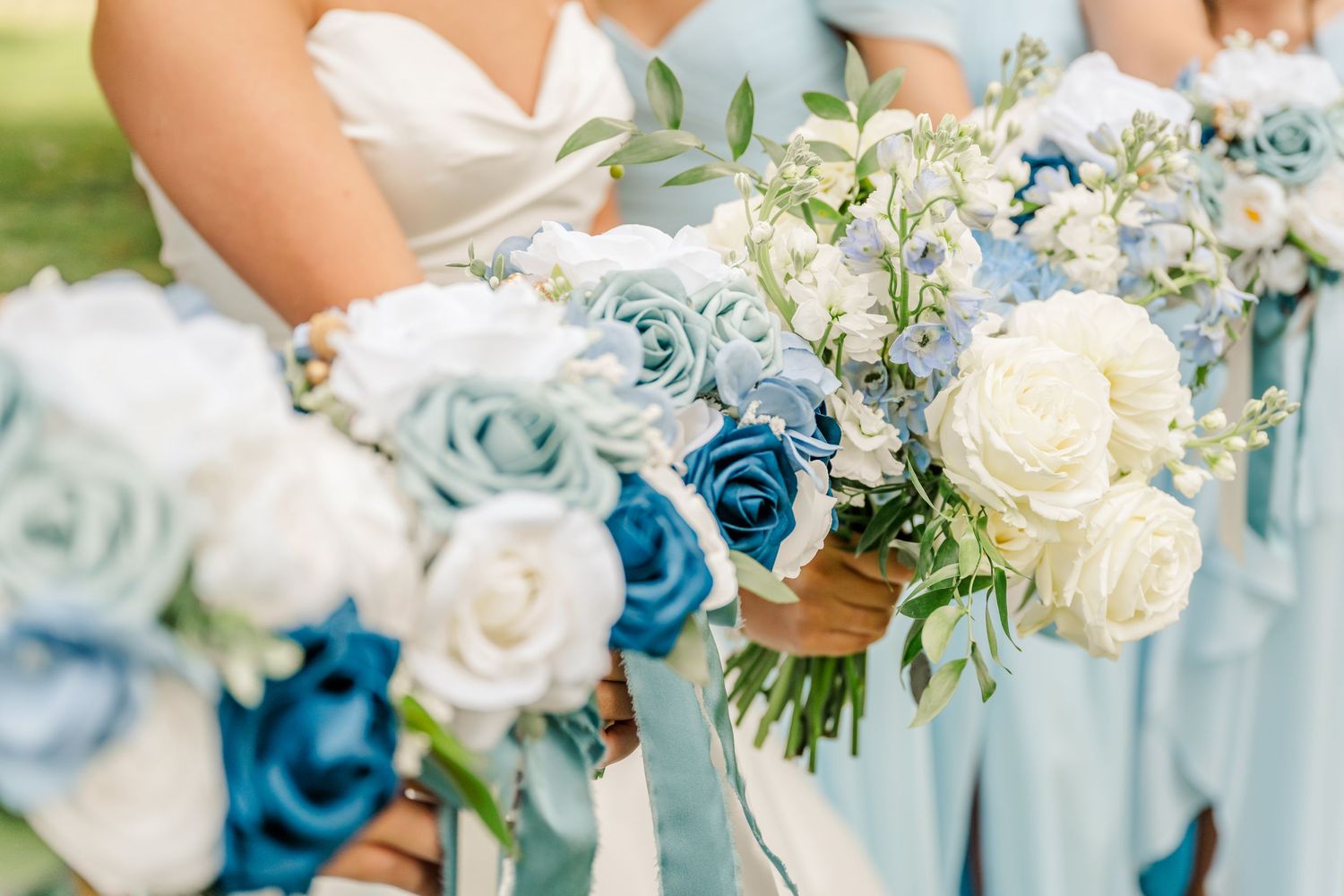 A row of elegant wedding bouquets in shades of blue and white roses with delicate greenery accents.
