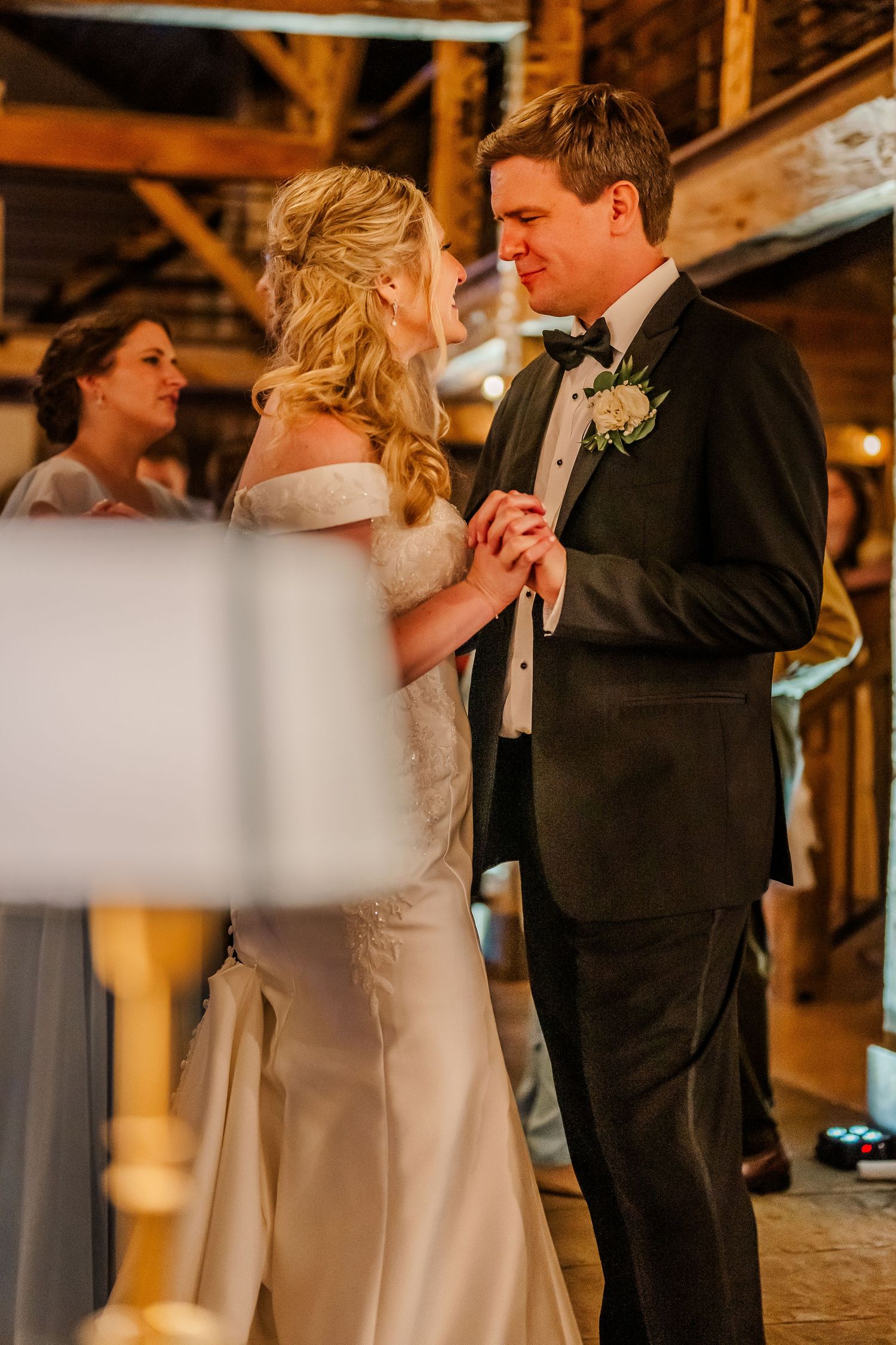 A couple shares a romantic first dance at their wedding reception in a warmly lit rustic venue.