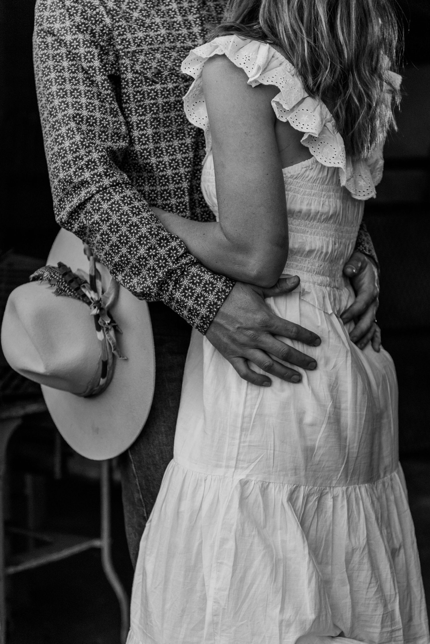 Black and white close-up of couple embracing in white dress and patterned shirt.