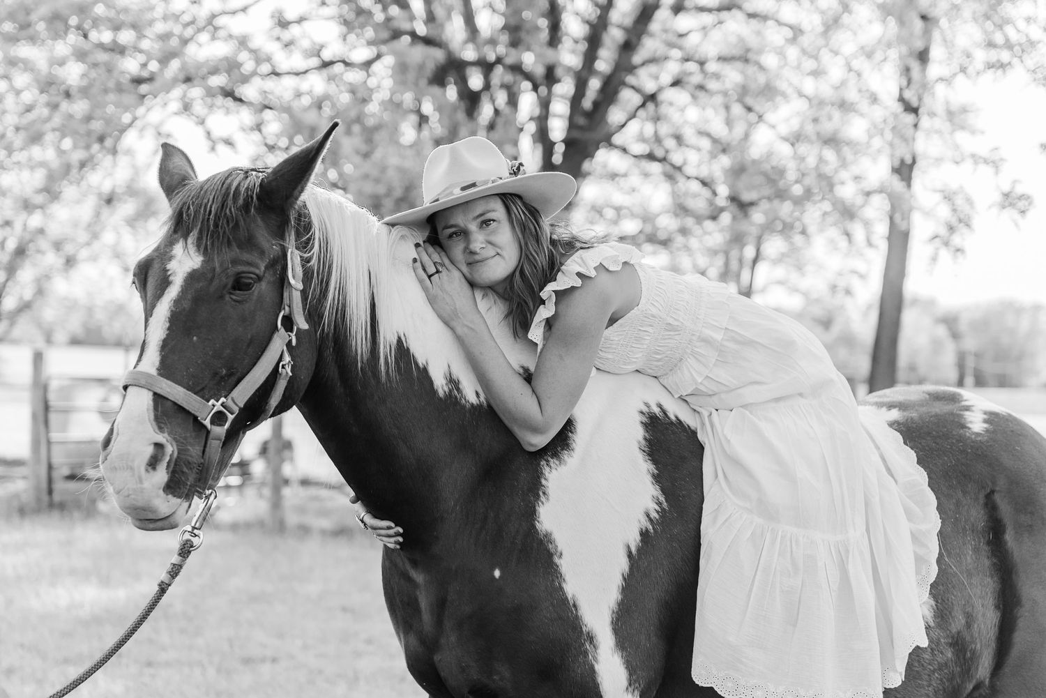 A black and white photograph shows a person riding a horse while wearing traditional equestrian attire.