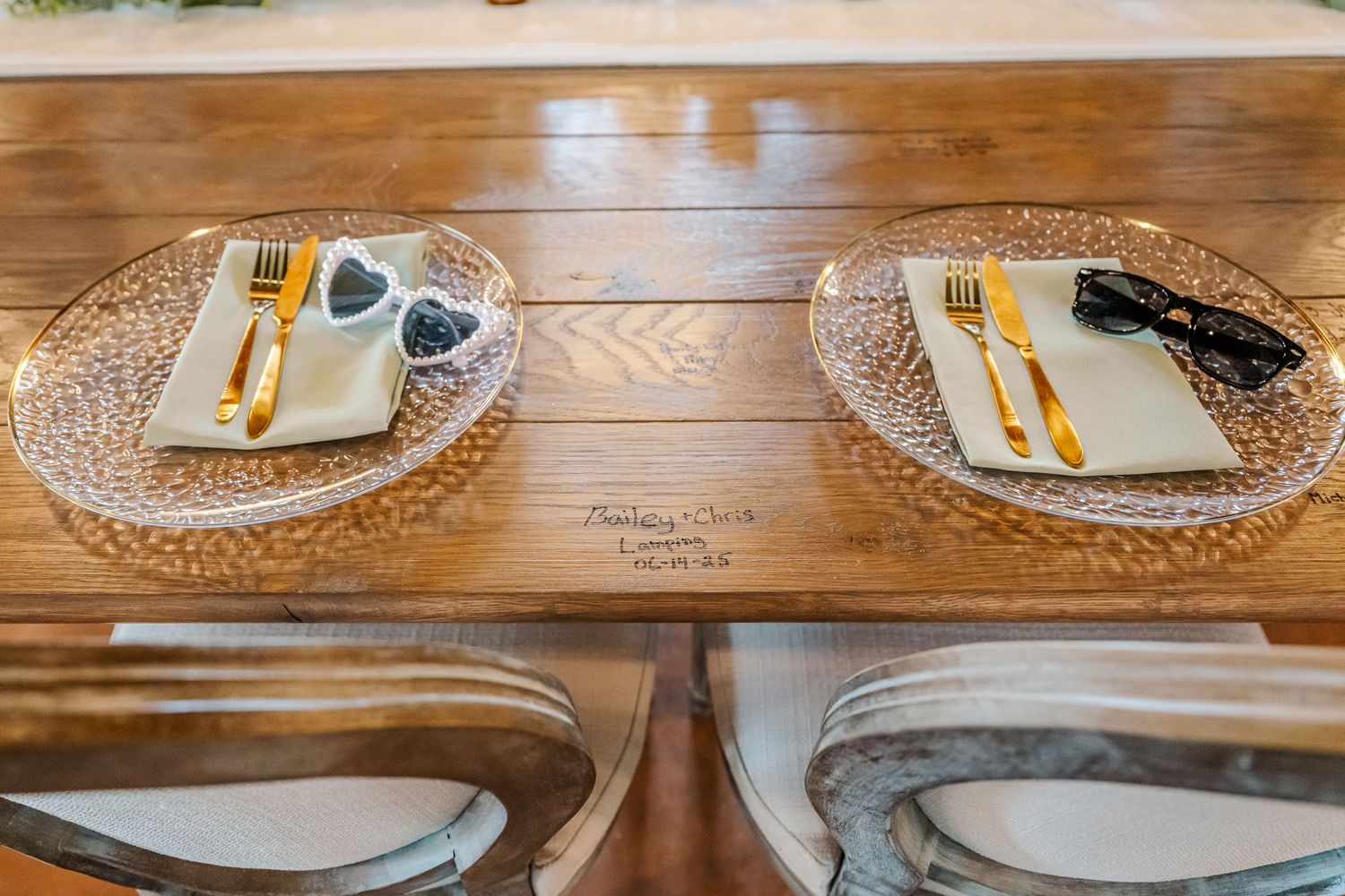 Place settings with gold cutlery and white plates arranged on woven placemats at a formal dining table.