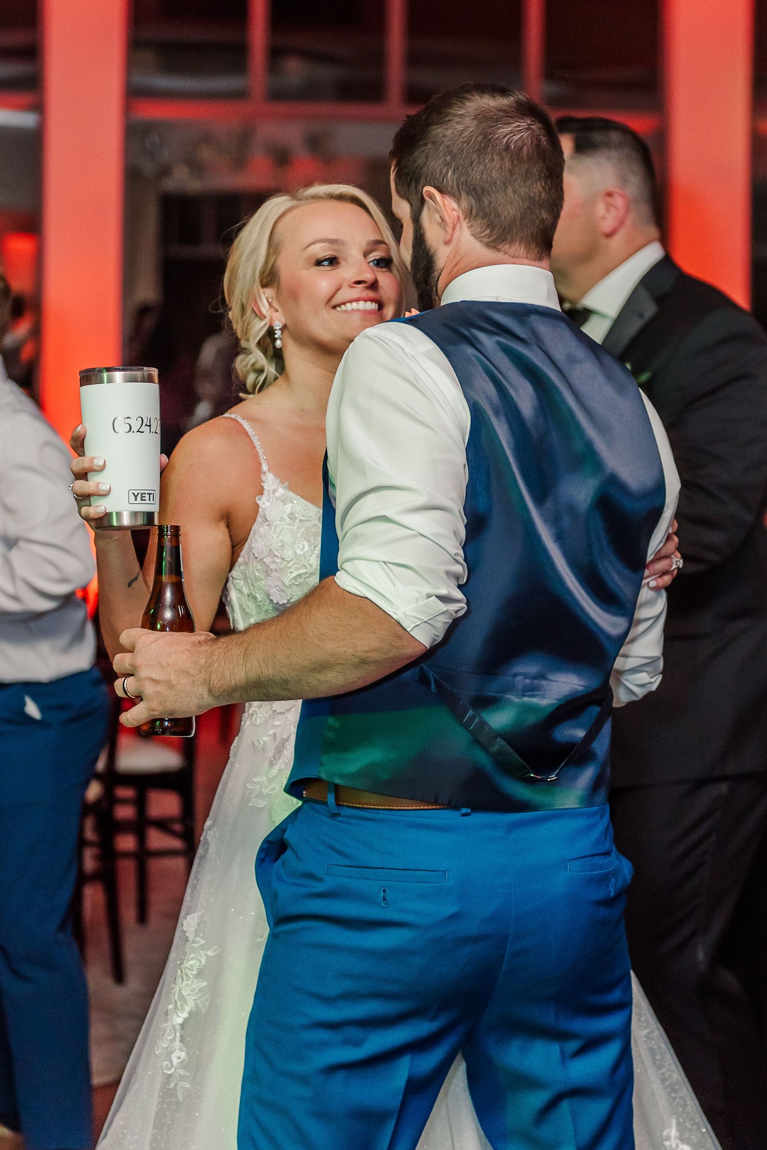 Wedding reception guests dancing and celebrating in a venue with dramatic red lighting.