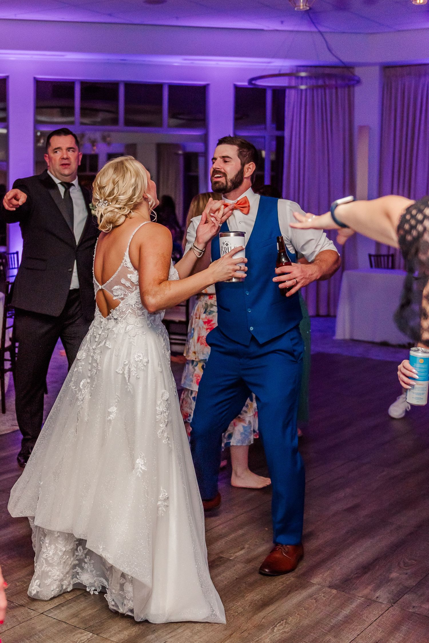 Wedding reception dance floor with purple lighting and couples dancing in formal attire.