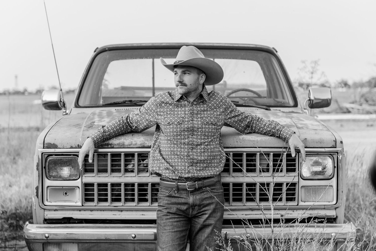 Black and white photo series showing someone in a cowboy hat sitting in a vintage pickup truck from different angles.