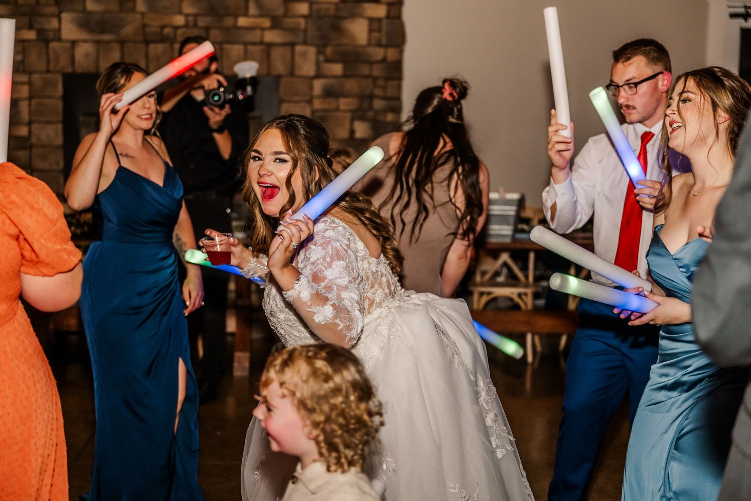 Wedding party members holding light sticks while dancing and celebrating at the reception.Four Seasons Barn Wedding & Event Venue