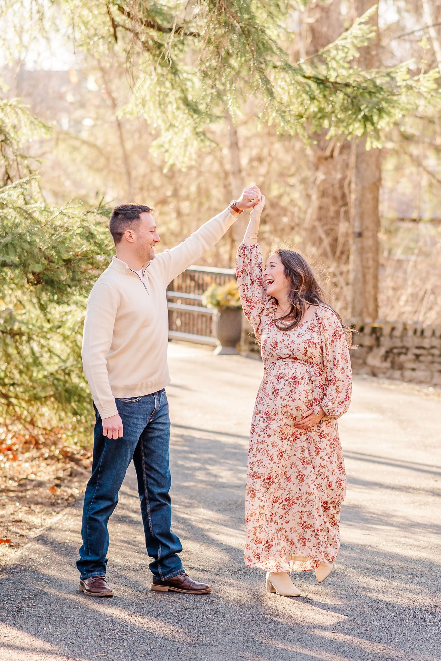 A couple dances and twirls together on a path surrounded by trees in autumn light.