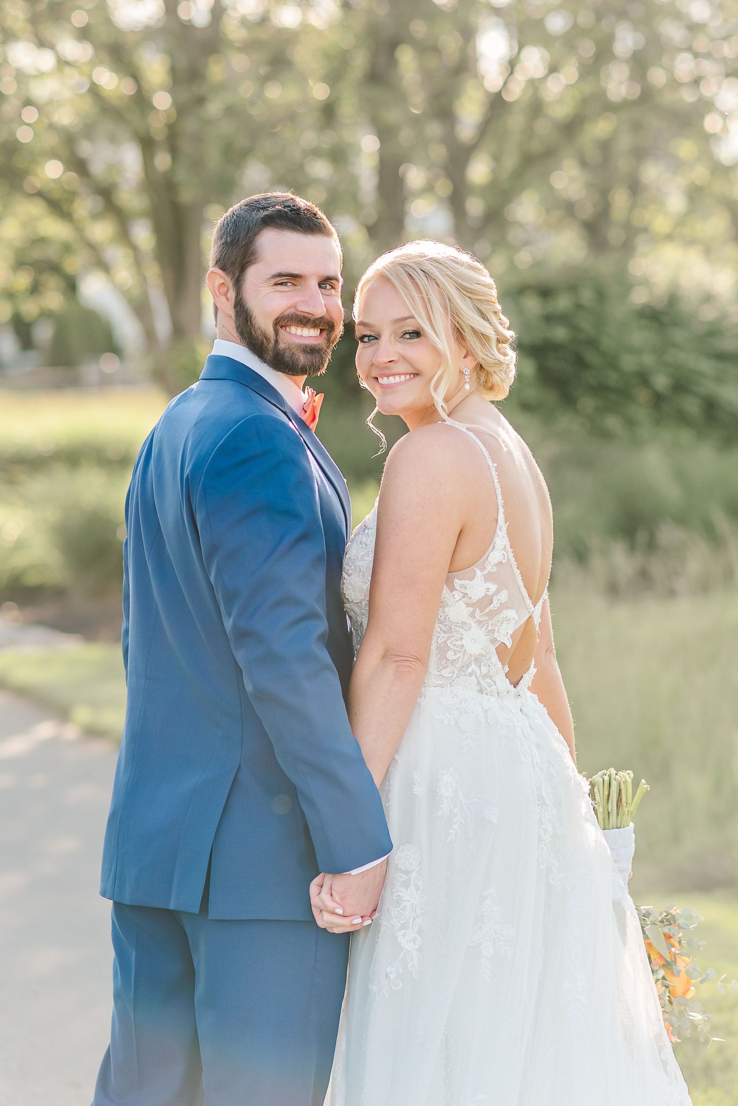 A couple in wedding attire share joyful moments together outdoors in a natural setting during golden hour.
