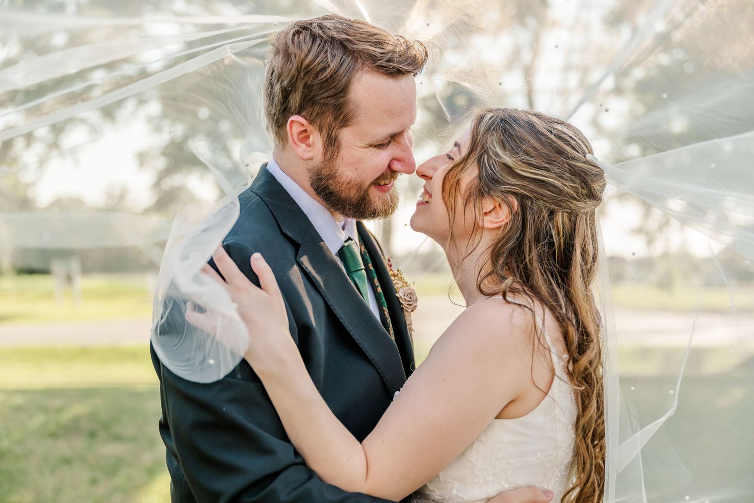 A romantic outdoor wedding photoshoot showing a couple embracing in a sunlit garden setting.