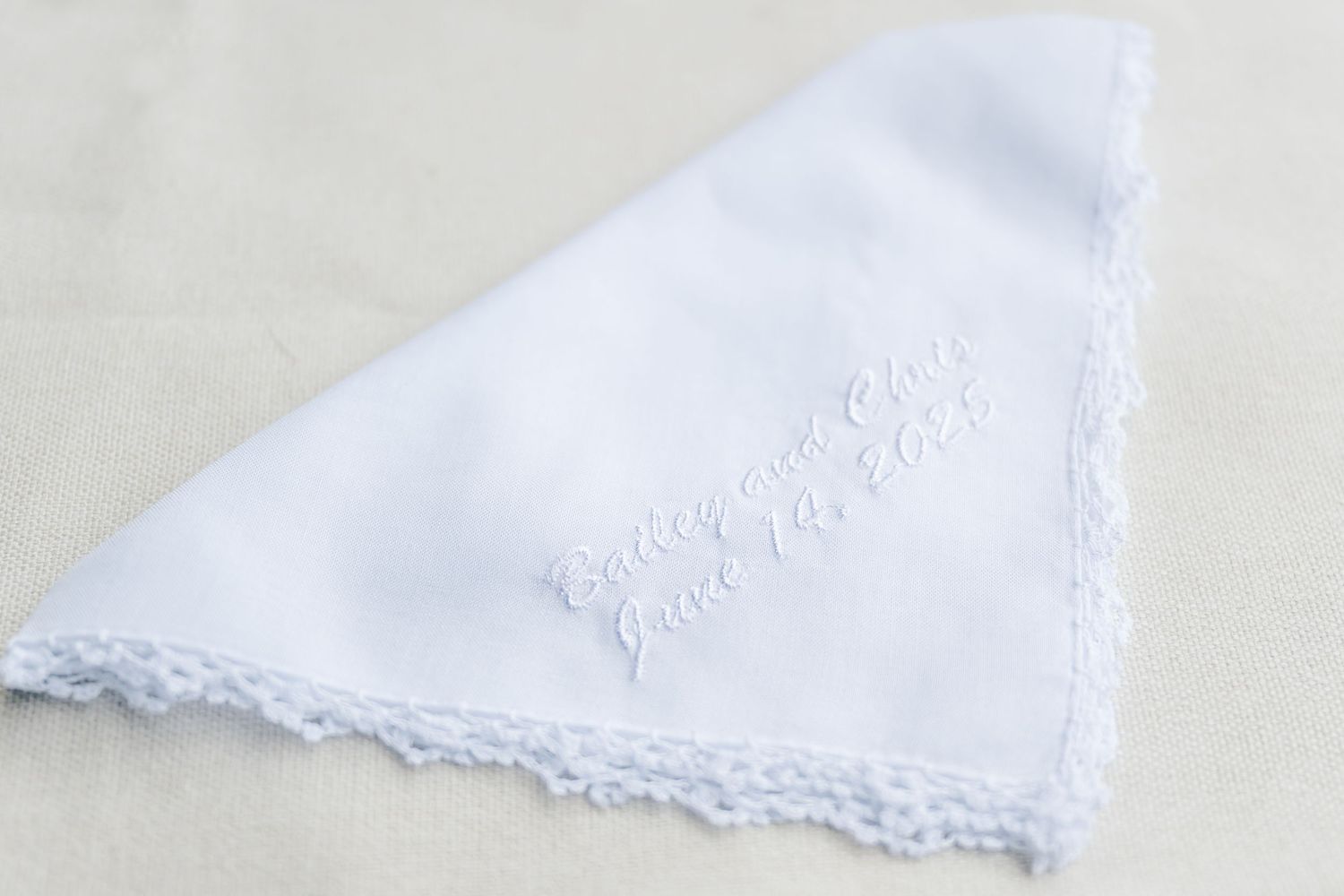 A delicate white handkerchief with embroidered details and lace trim along the edges.