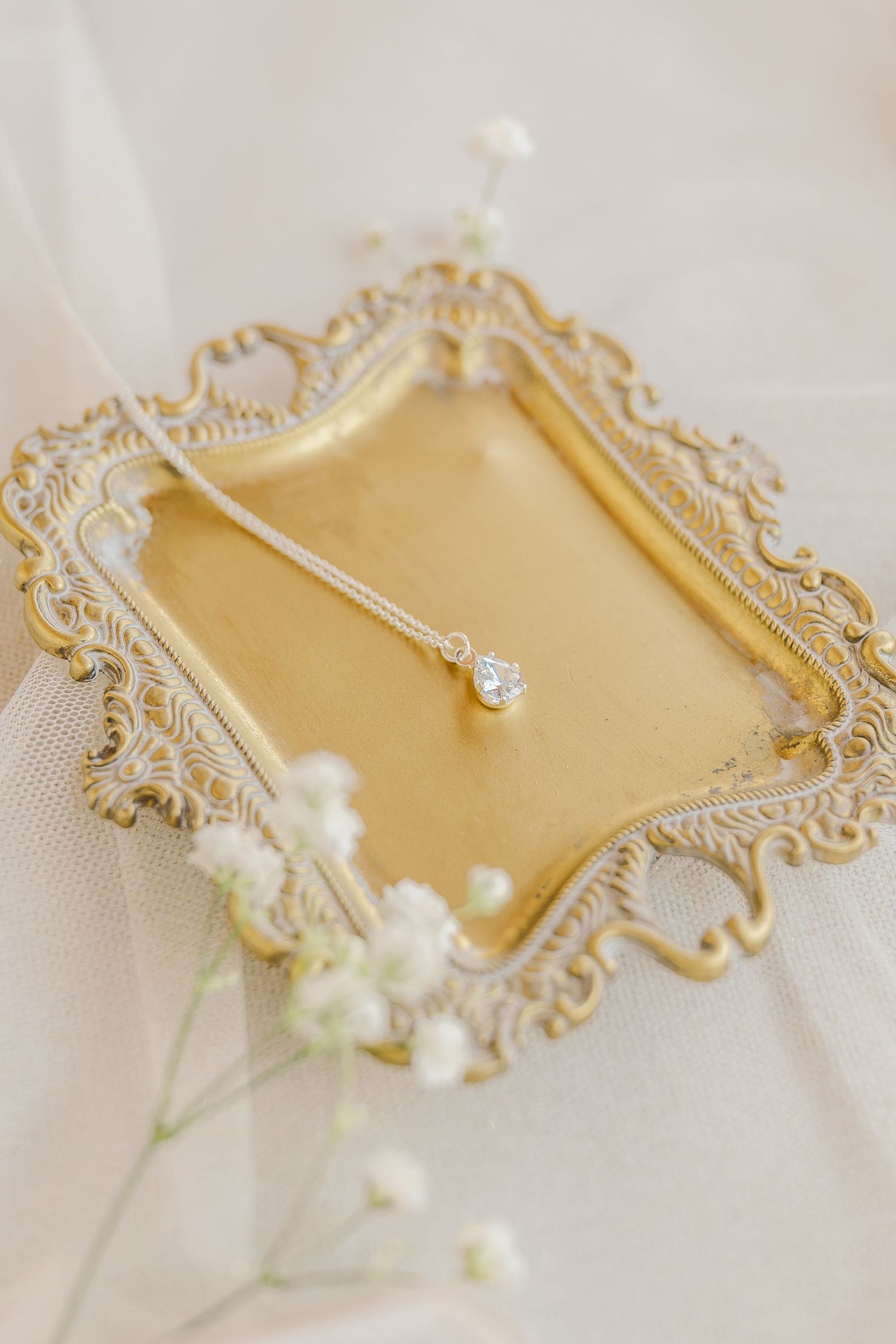 Elegant gold ornate picture frame with delicate white baby's breath flowers against a light neutral background.
