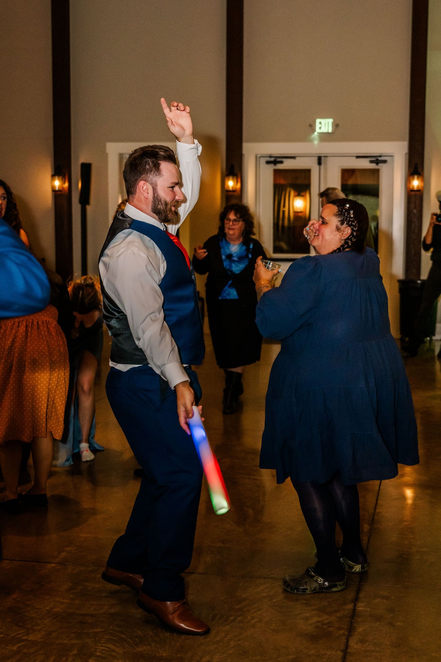 Wedding guests dance with glowing light sticks on a dark dance floor at an evening reception.Four Seasons Barn Wedding & Event Venue