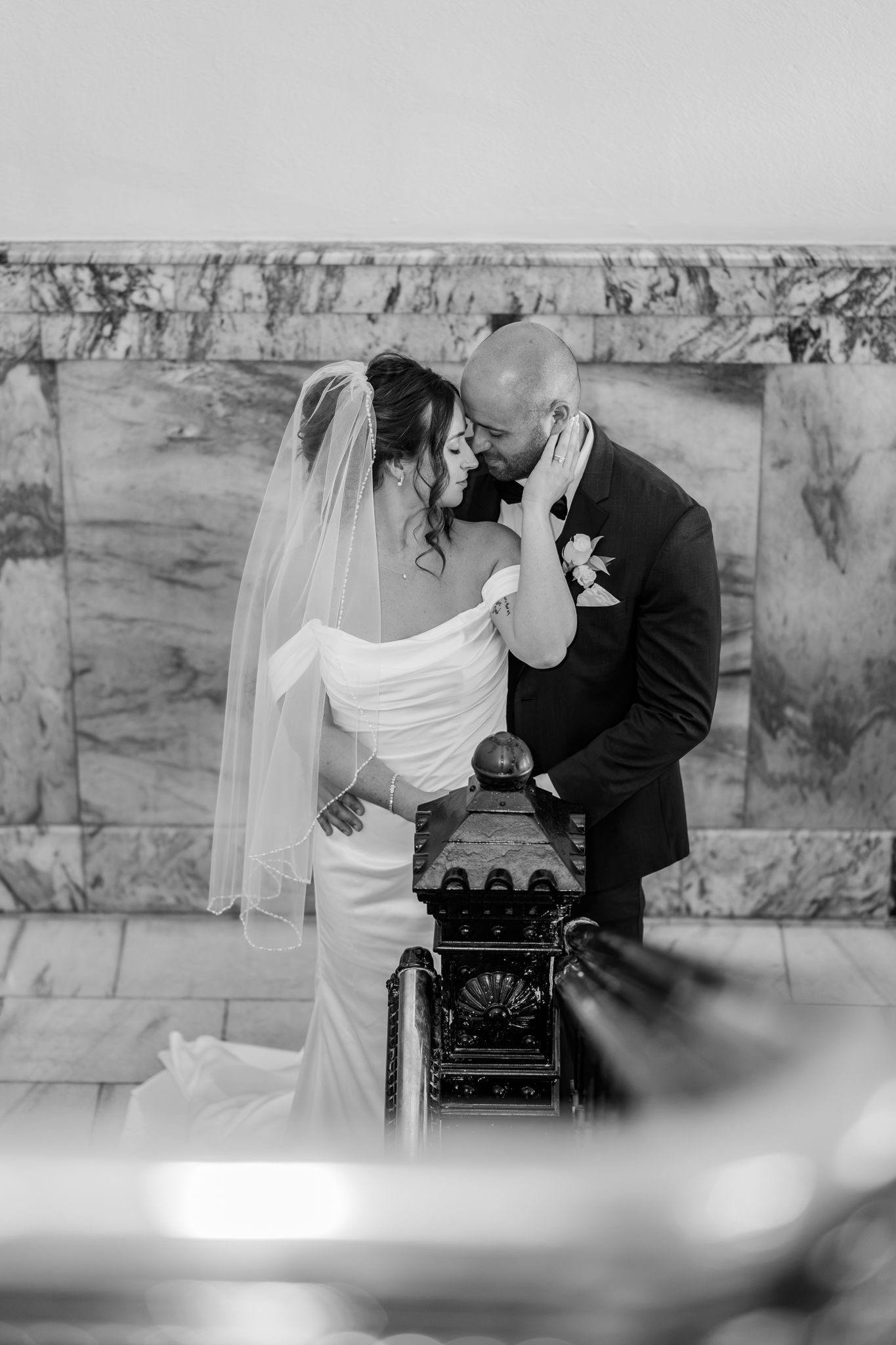Black and white wedding photo of bride and groom sharing an intimate moment, with marble wall backdrop. PIckaway Country courthouse wedding.