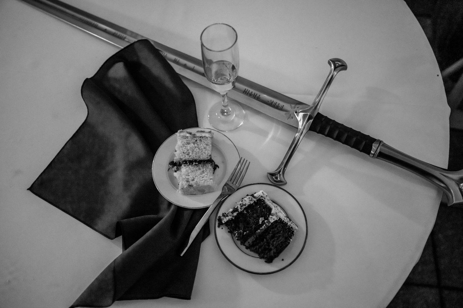 Elegant table settings at a formal dinner party with wine glasses and dark place settings against a light background.