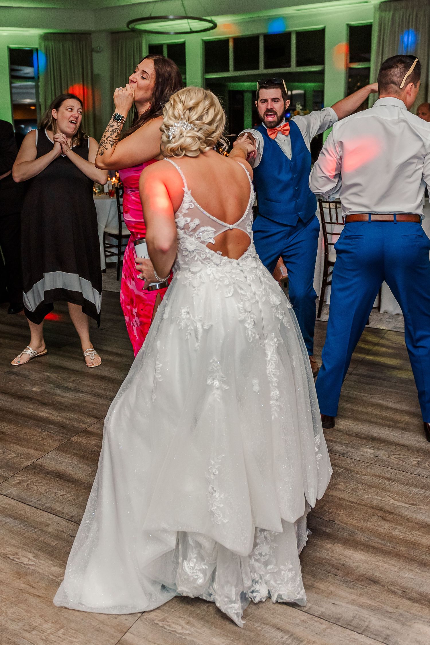 Wedding guests dancing and celebrating on the dance floor at an indoor reception venue.