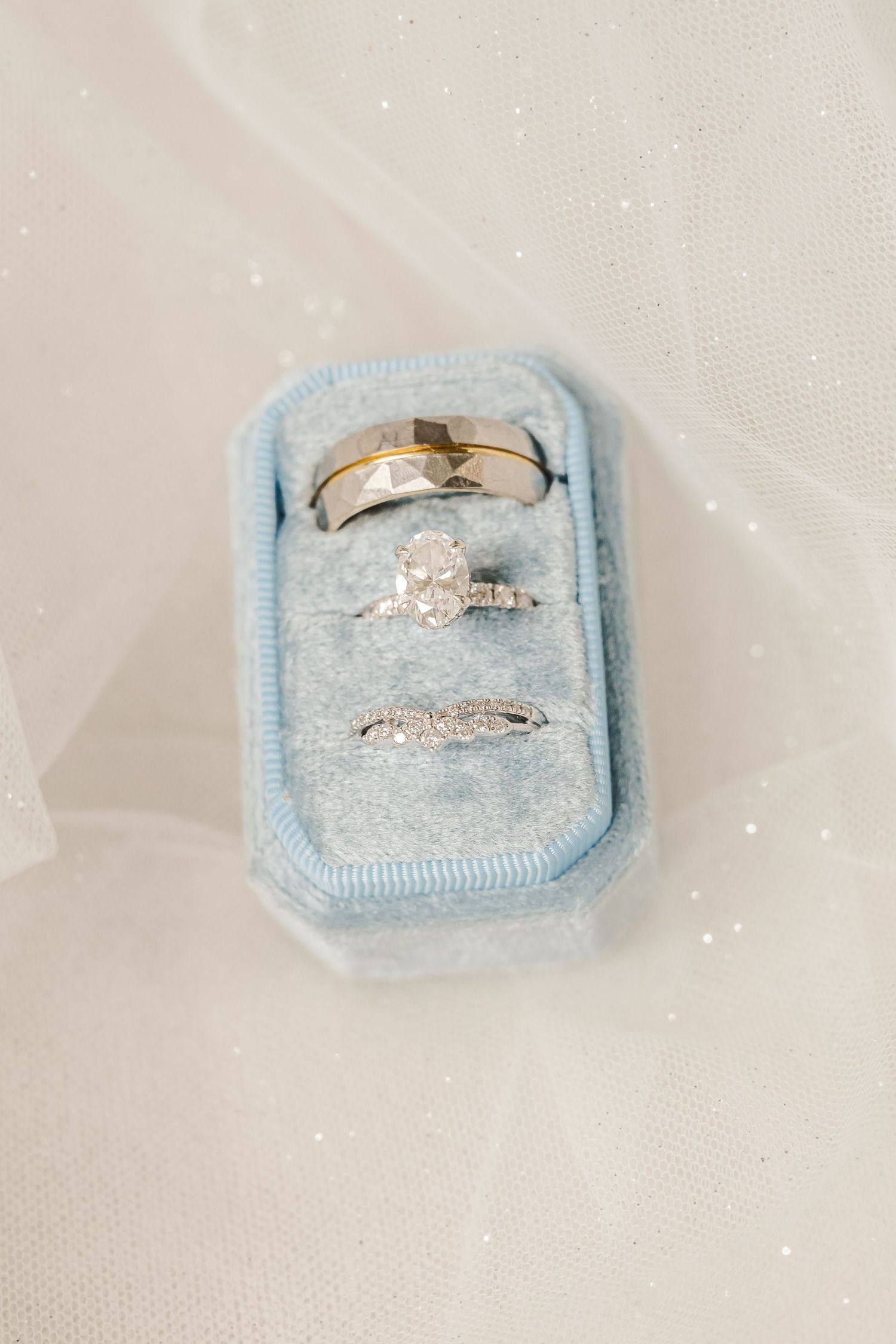 Elegant engagement ring with diamond solitaire displayed in light blue velvet ring box.Four Seasons Barn Wedding & Event Venue