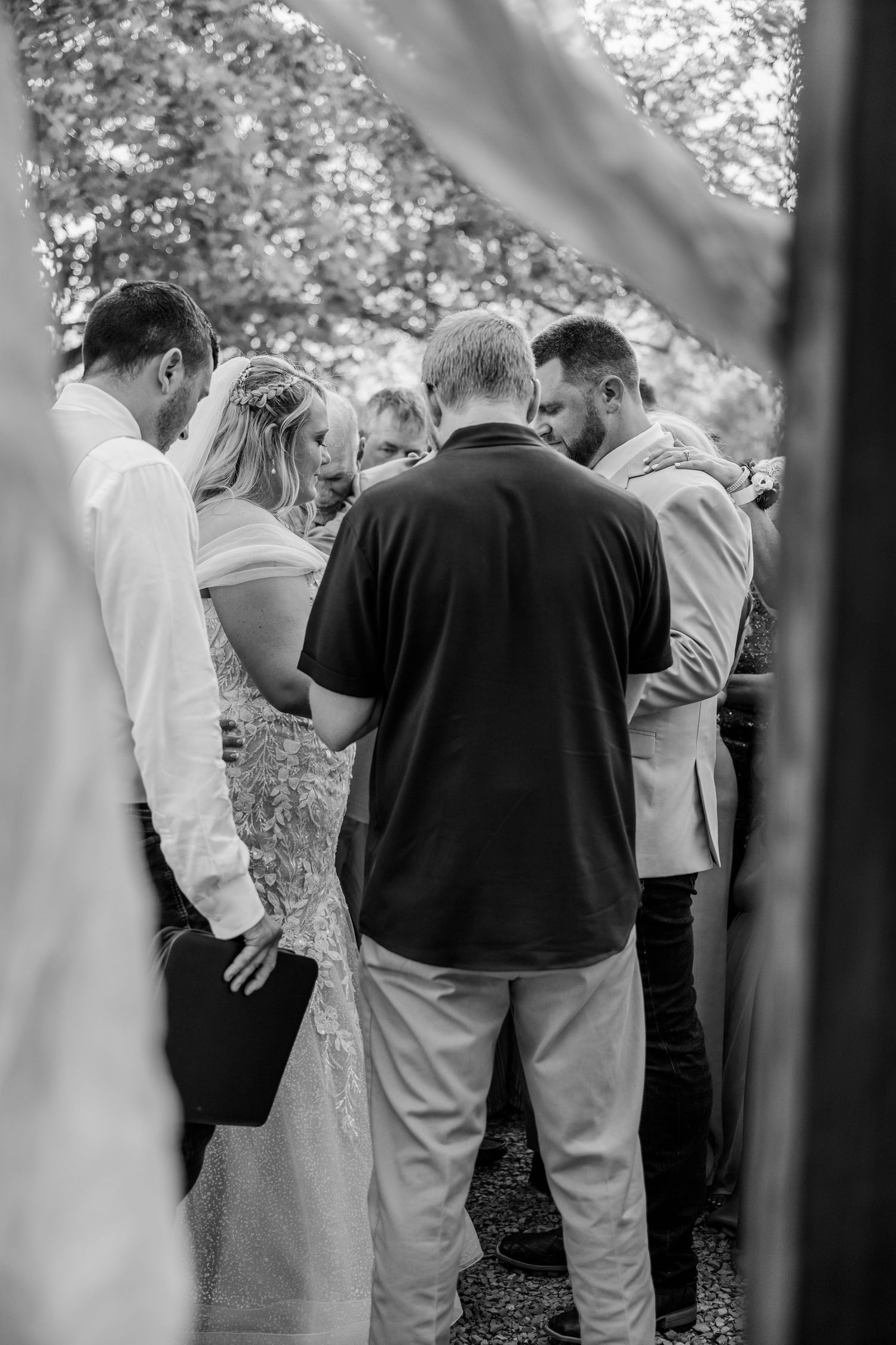 Intimate gathering during an outdoor wedding ceremony captured through natural foliage.