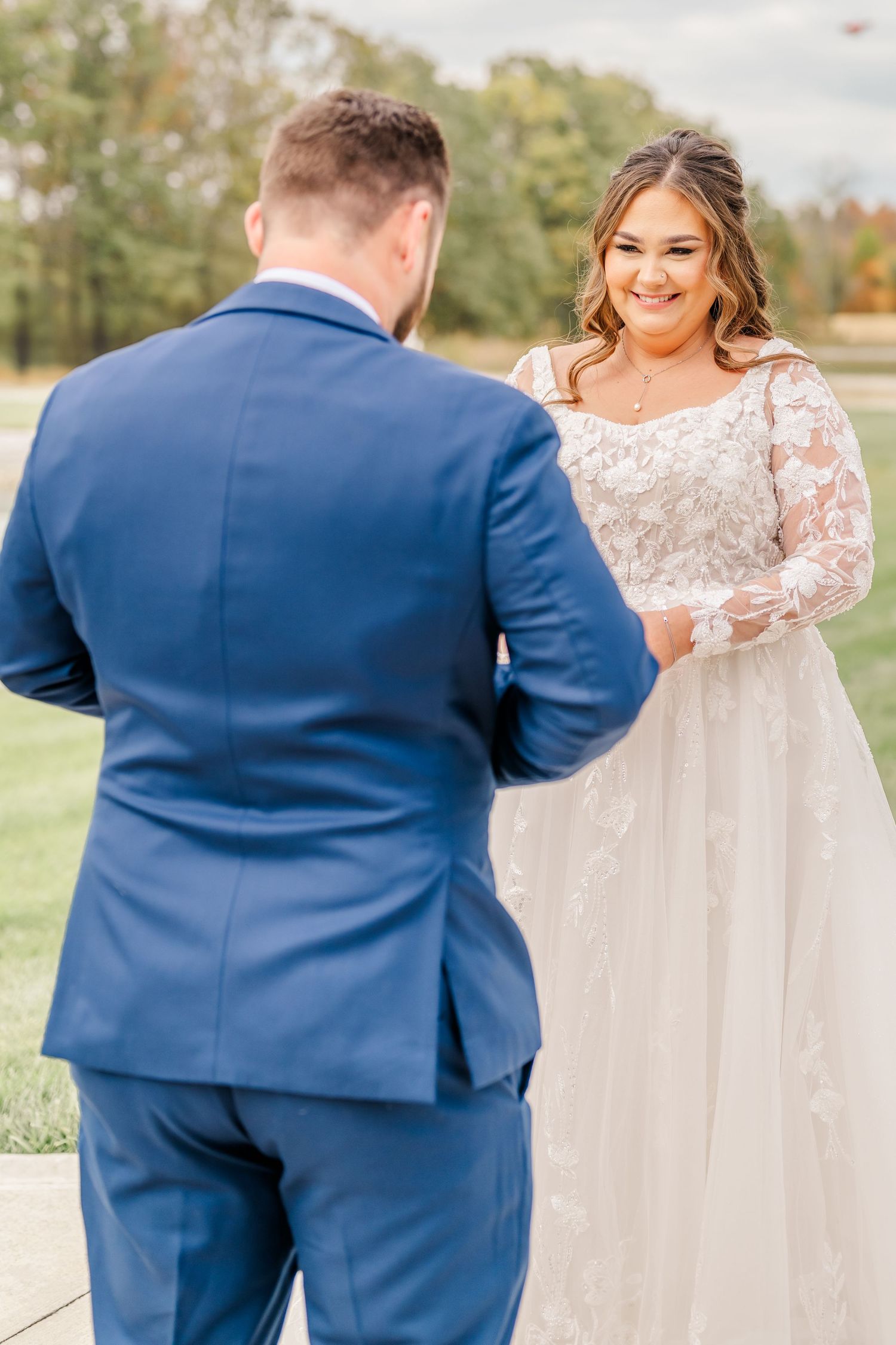 A couple in wedding attire share a playful moment along an outdoor covered walkway.