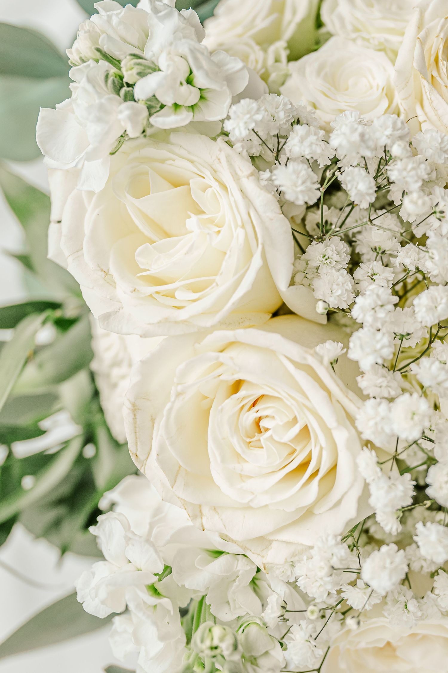 Close-up macro shots of elegant white roses and baby's breath flowers arranged in a romantic wedding bouquet.