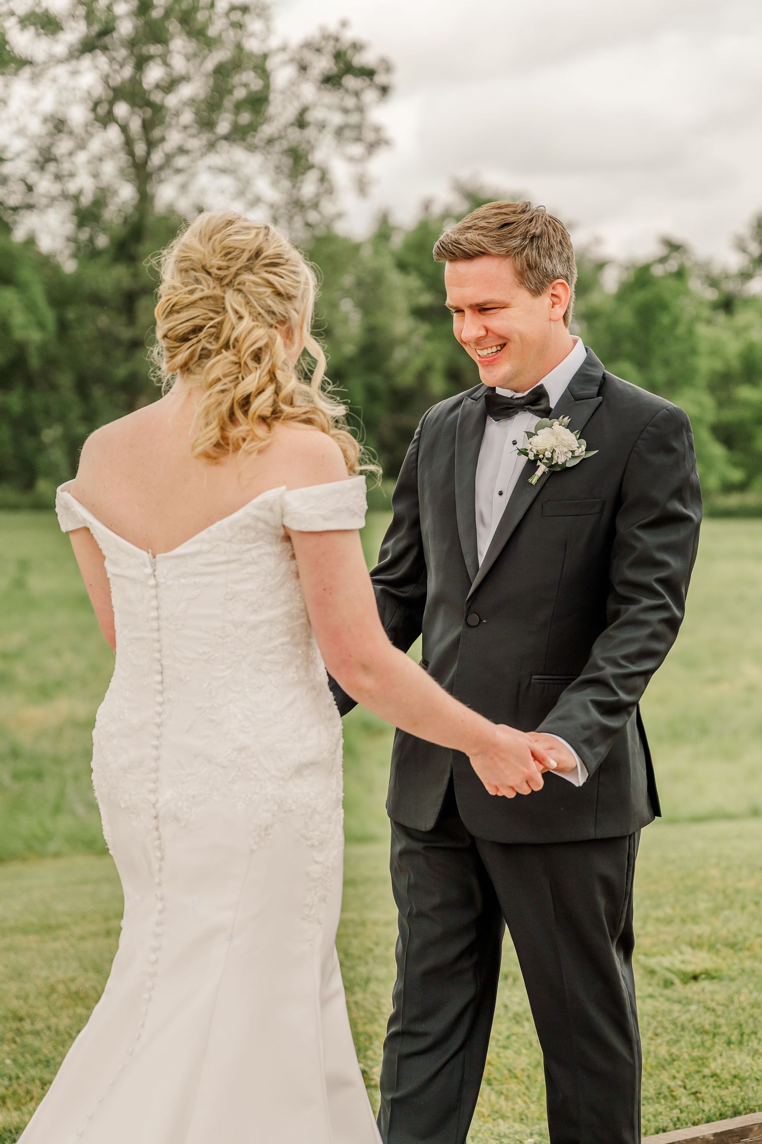 A couple shares a joyful moment during their first look on a green lawn. The Old Barns at Dry Run Farms in Williamsport, OH.