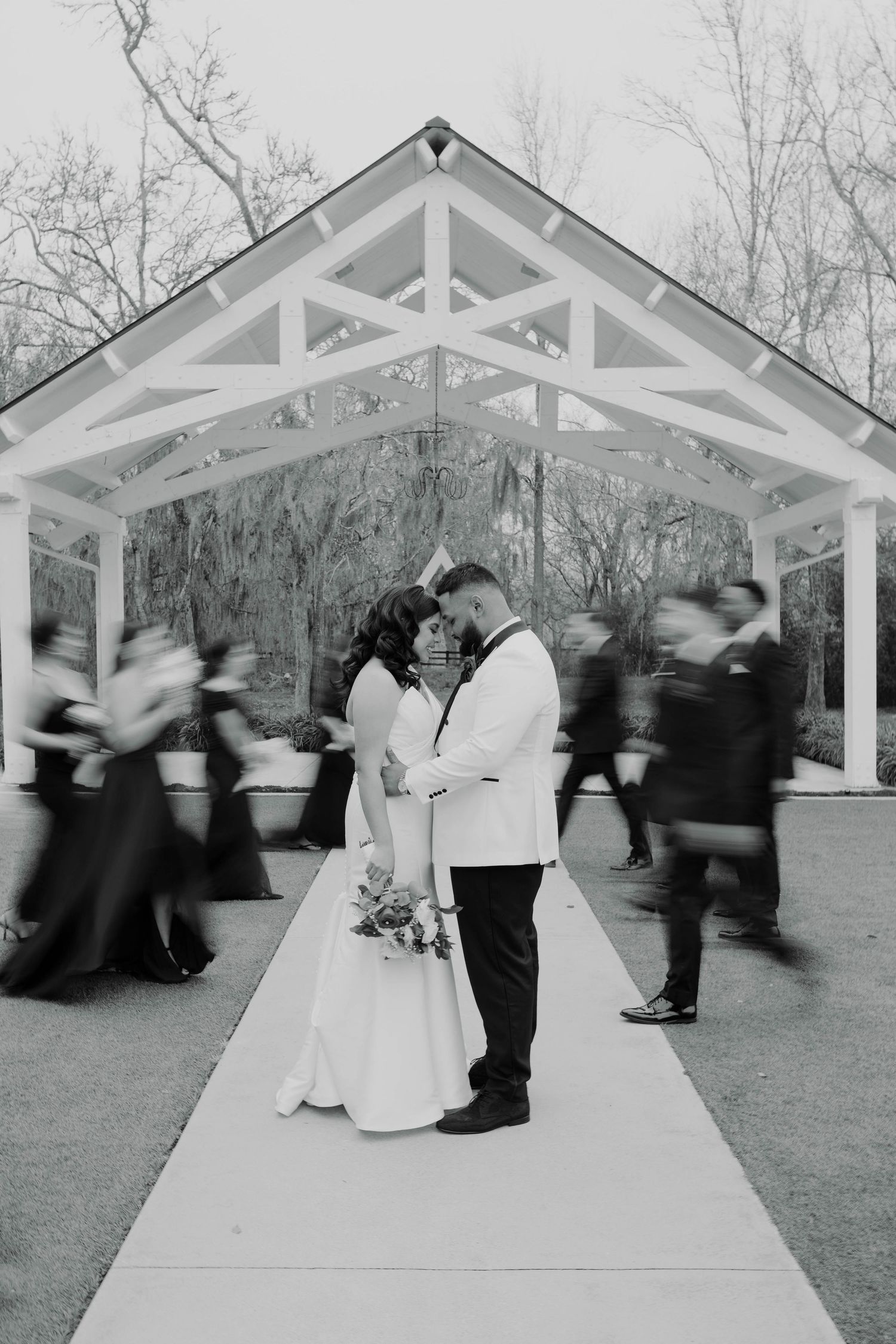 Motion blur sequence captures wedding party dancing and moving under white outdoor gazebo.