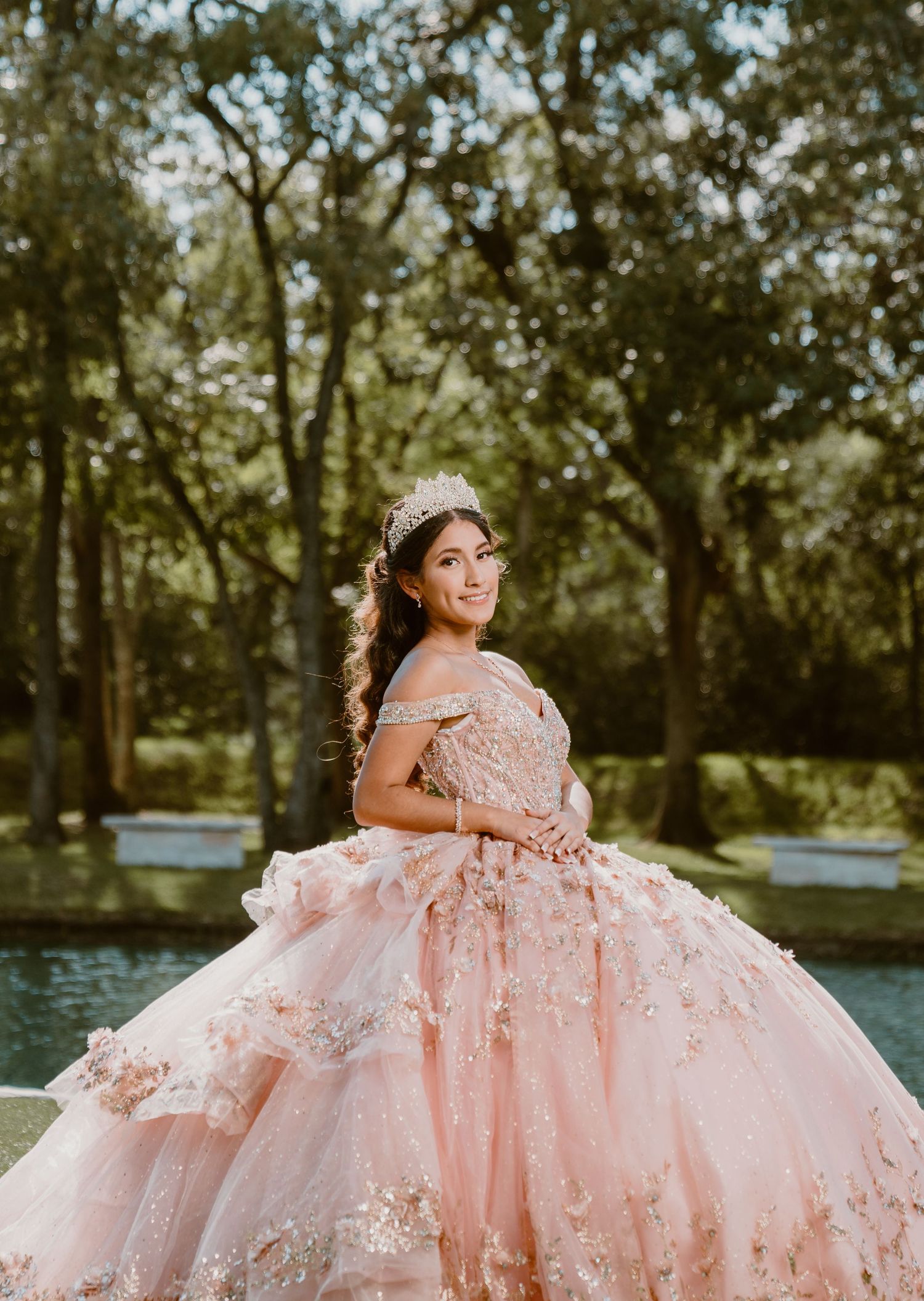 Pink princess ballgown with floral details captured in outdoor garden setting.