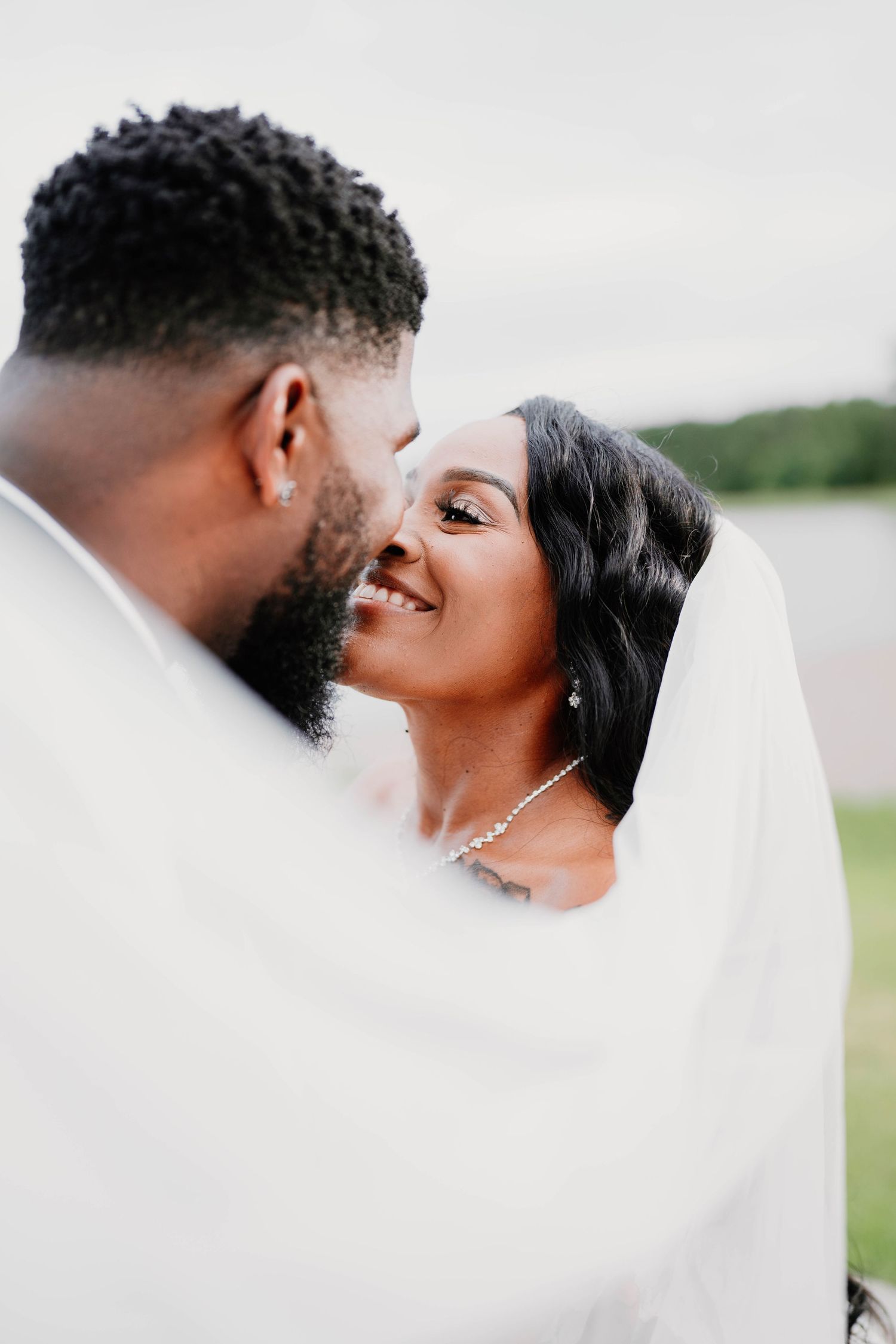 Romantic wedding couple embracing under a flowing white veil.