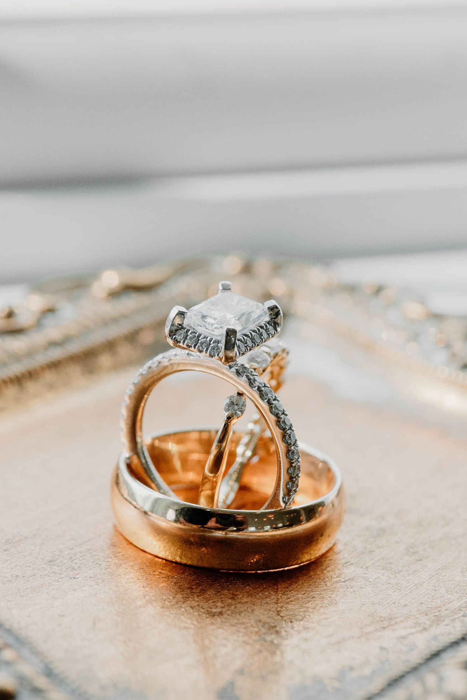Wedding rings nestled together on a textured metallic surface.