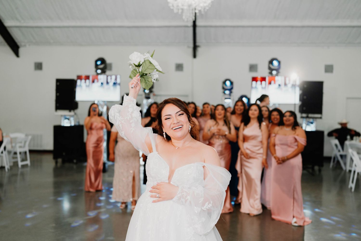 Wedding reception venue with white decor and stage lighting setup.