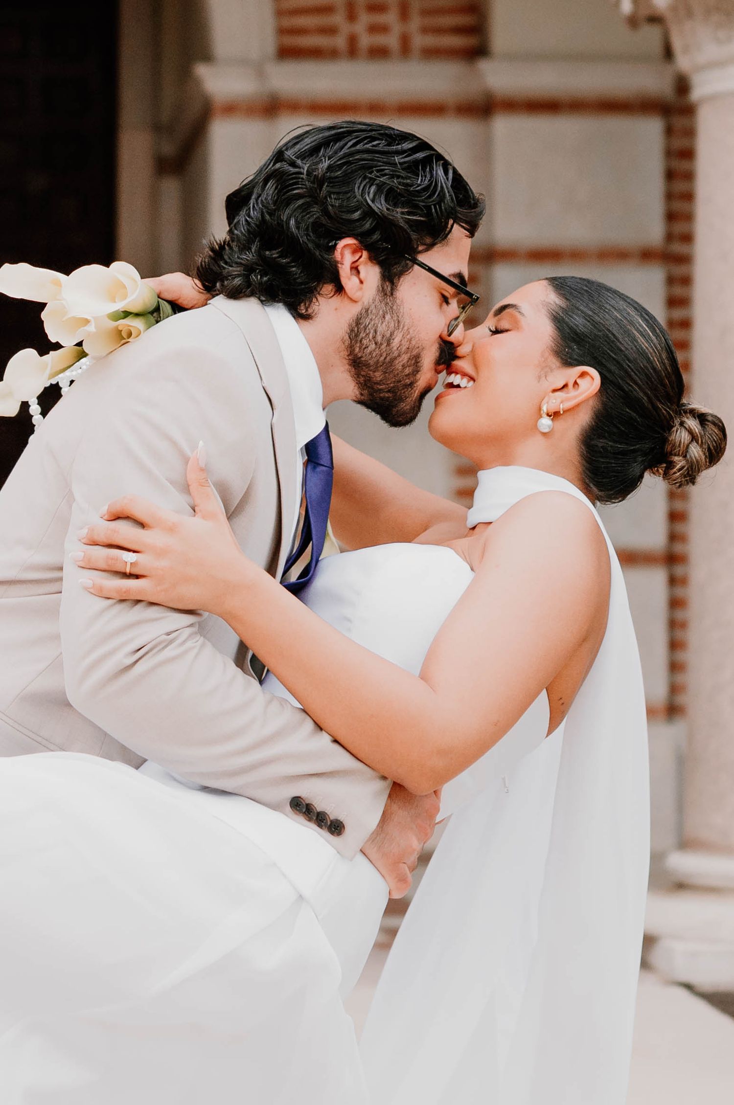 Newlyweds share intimate kisses in a series of romantic poses against brick architecture.