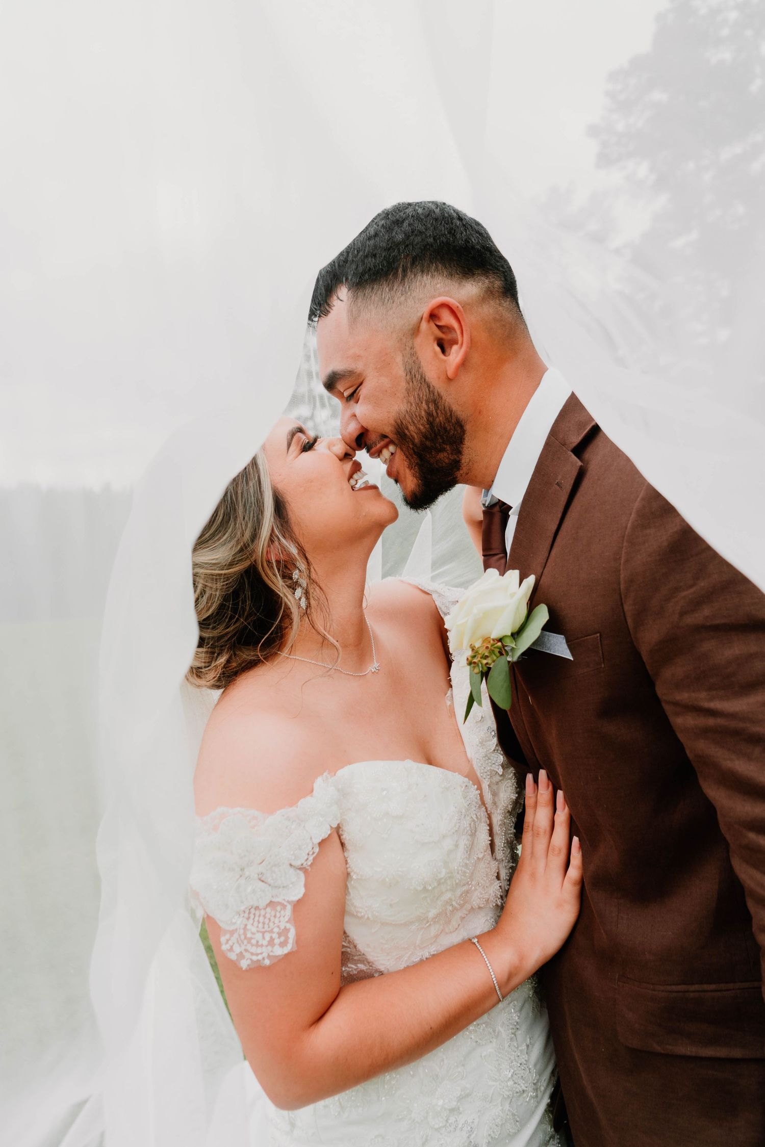 A tender wedding moment captured with soft lighting and a white floral boutonniere.