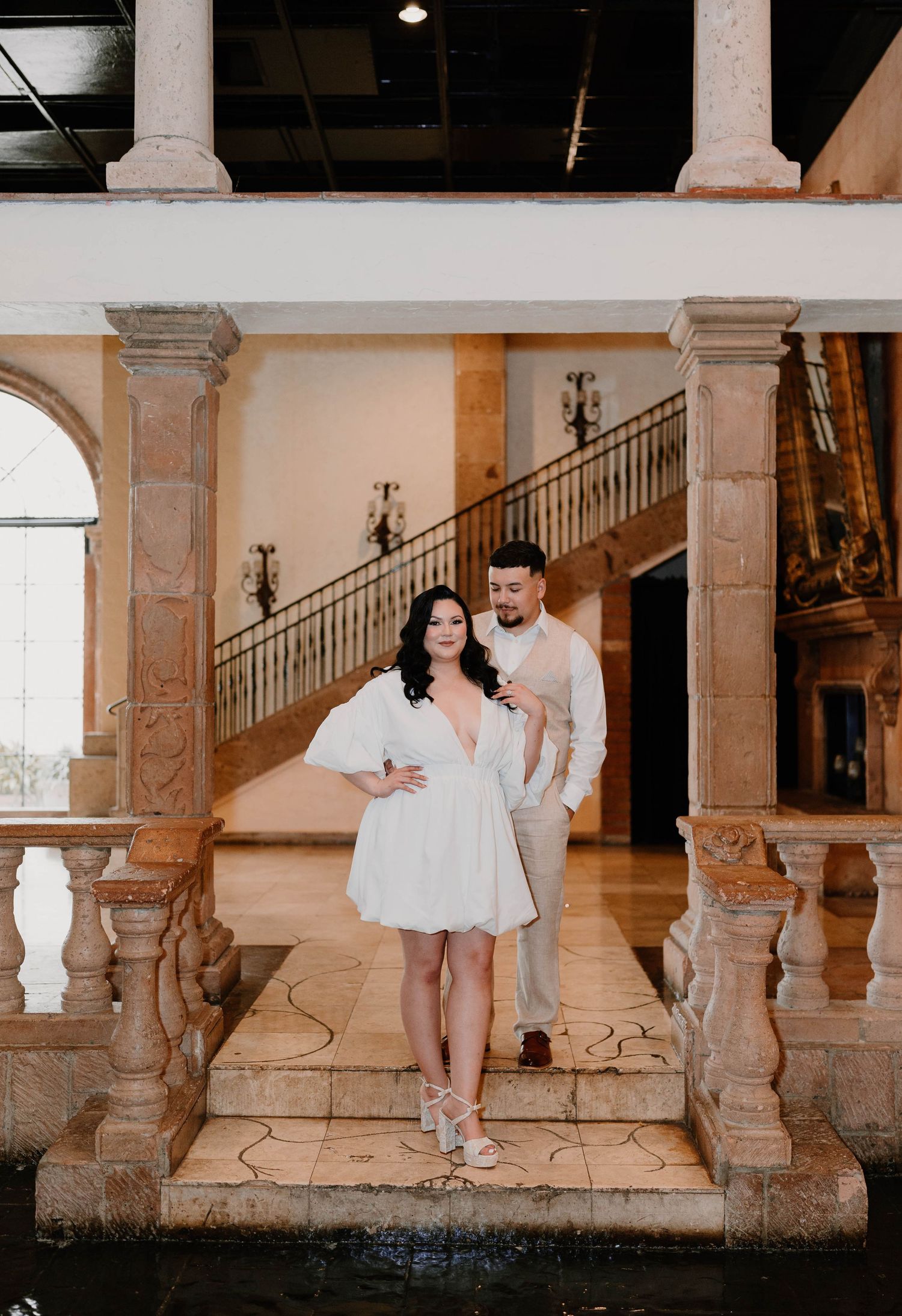 Couple poses playfully in a series of romantic shots against an ornate stone colonnade.