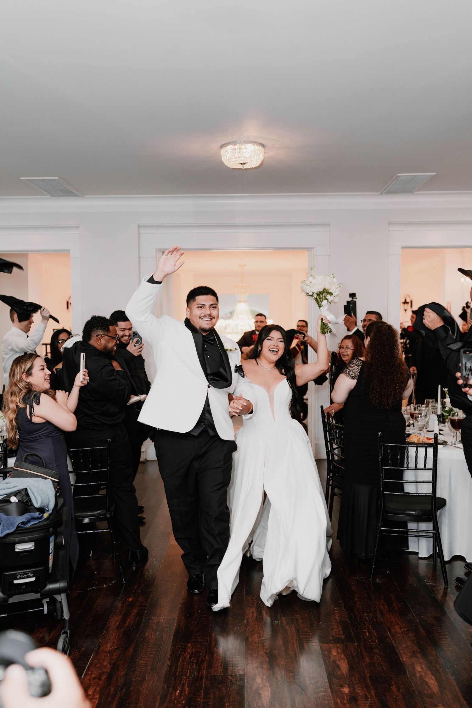 Wedding reception guests dancing and celebrating in an elegant white ballroom.