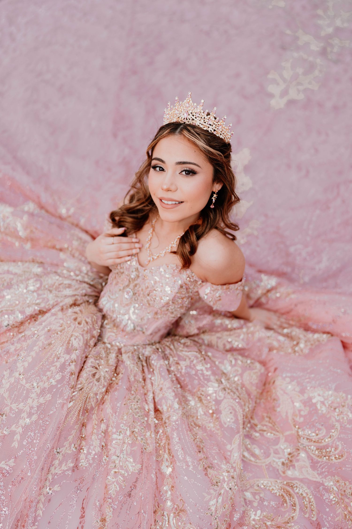 Pink sequined gown and tiara create magical princess moment against pink backdrop.