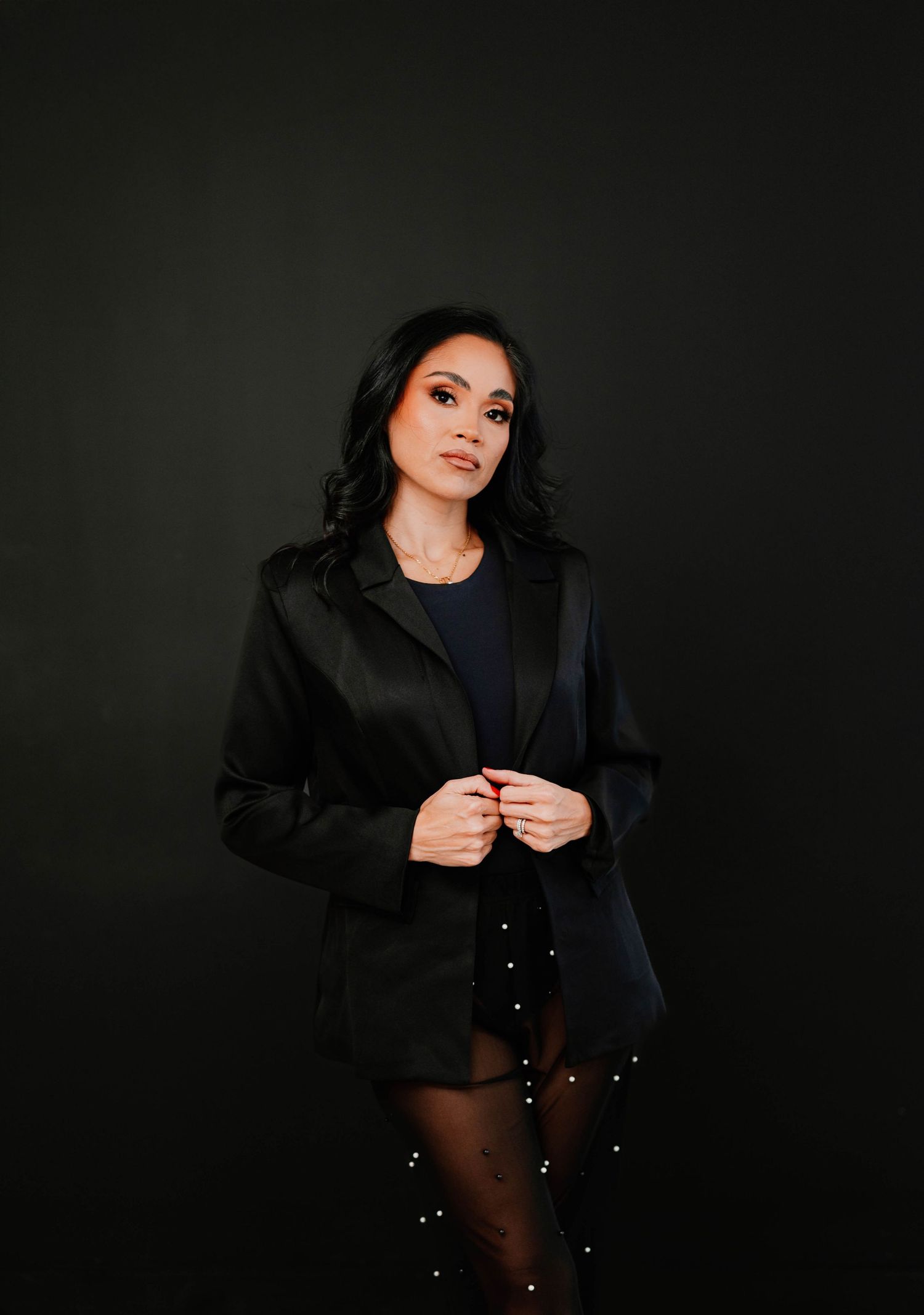 Artistic dark portrait session featuring woman in black outfit against black background.