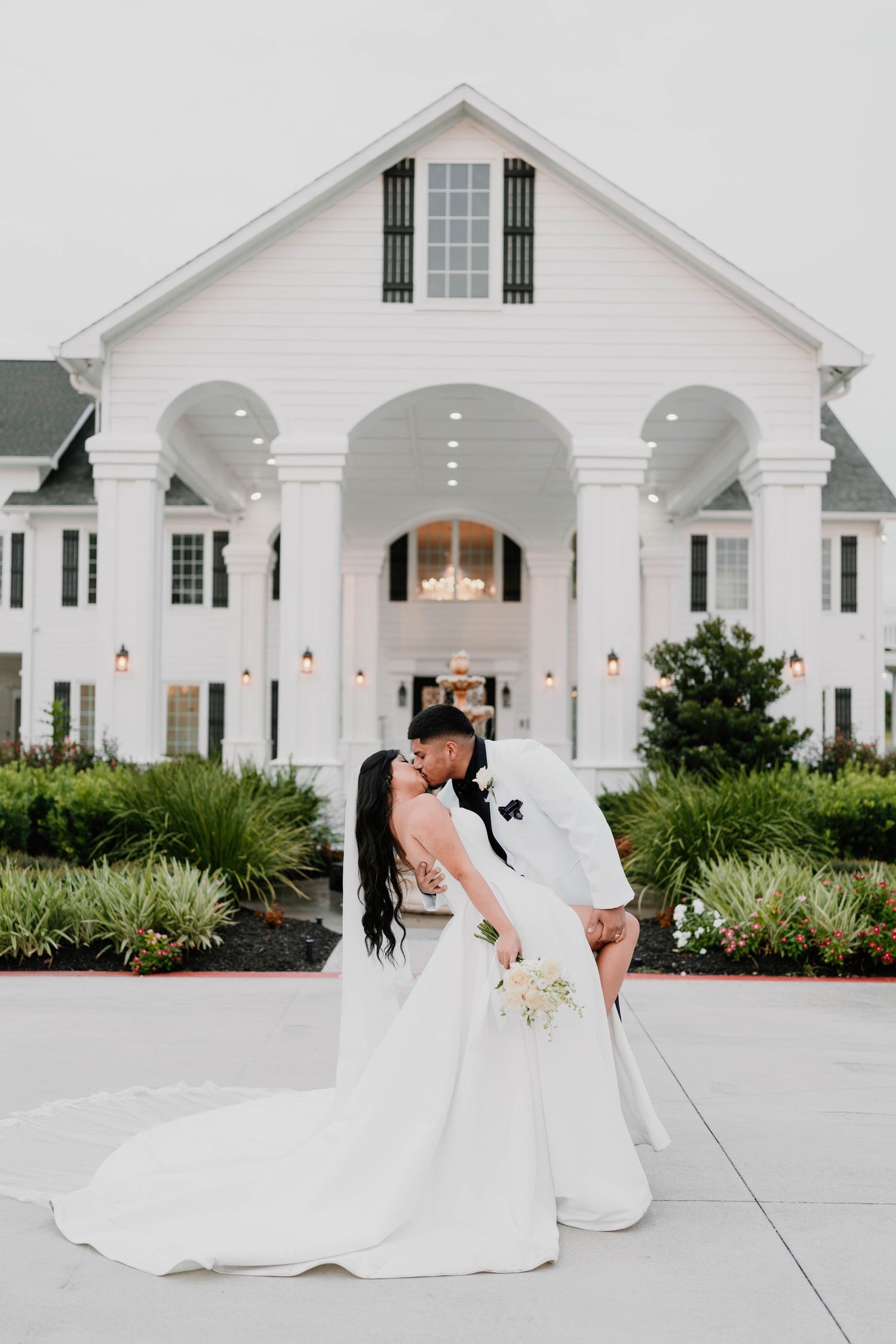 Newlyweds sharing romantic moment outside elegant white chapel building.