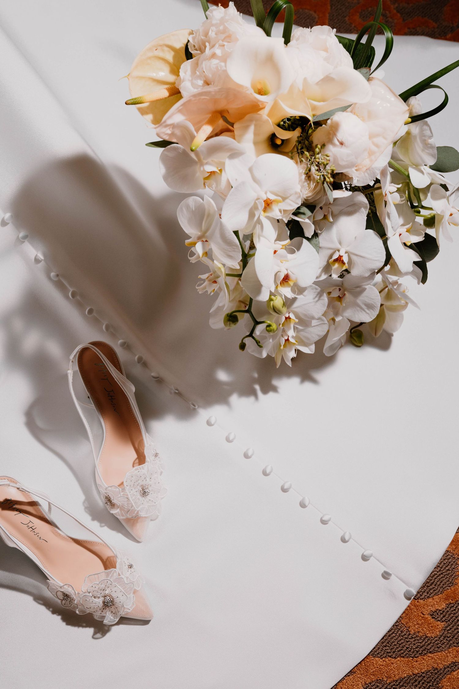 White roses and delicate floral arrangements cast soft shadows against a light background in an elegant composition.