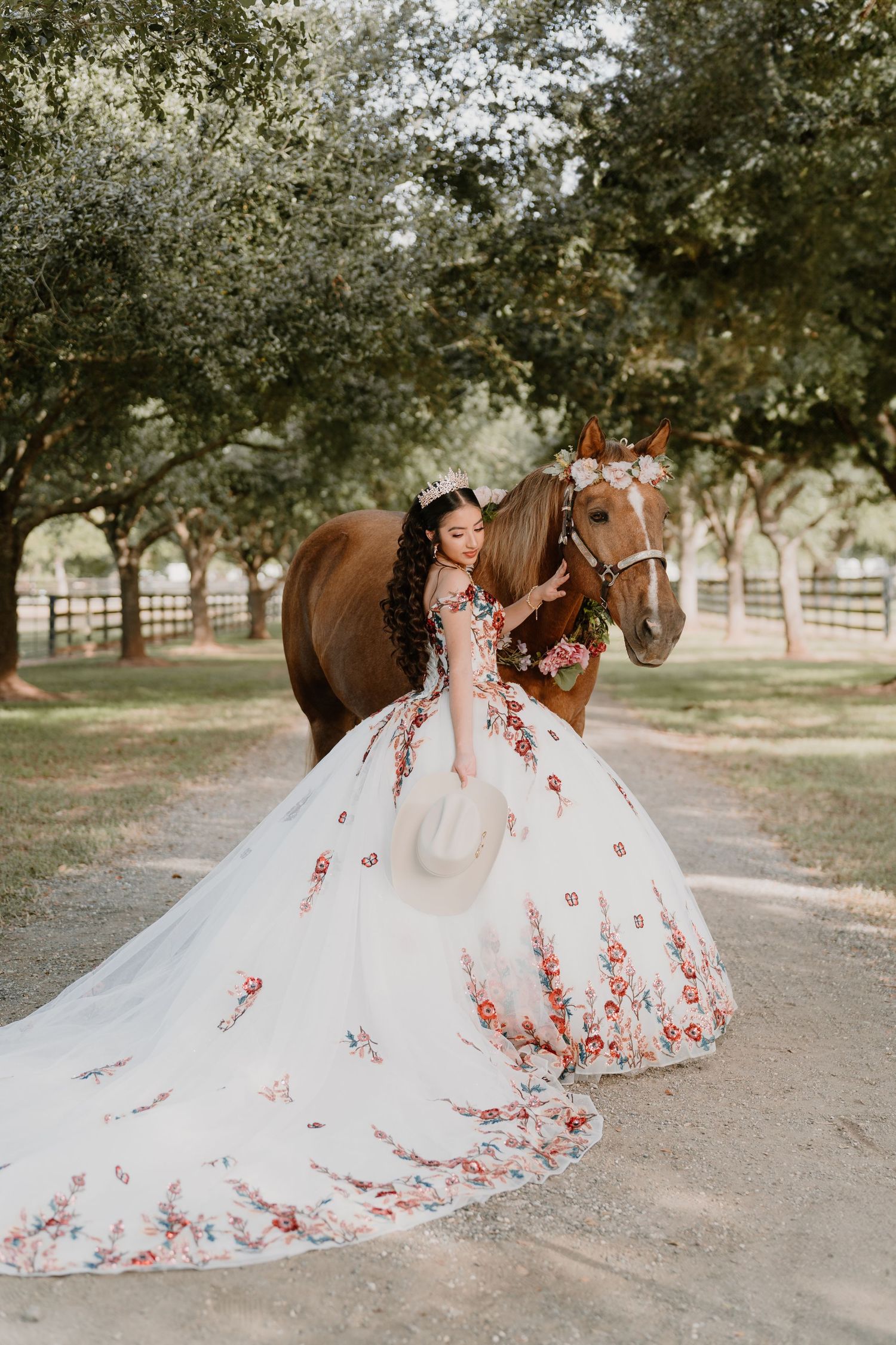 Elegant white and pink floral ballgown photographed with horse in countryside setting.